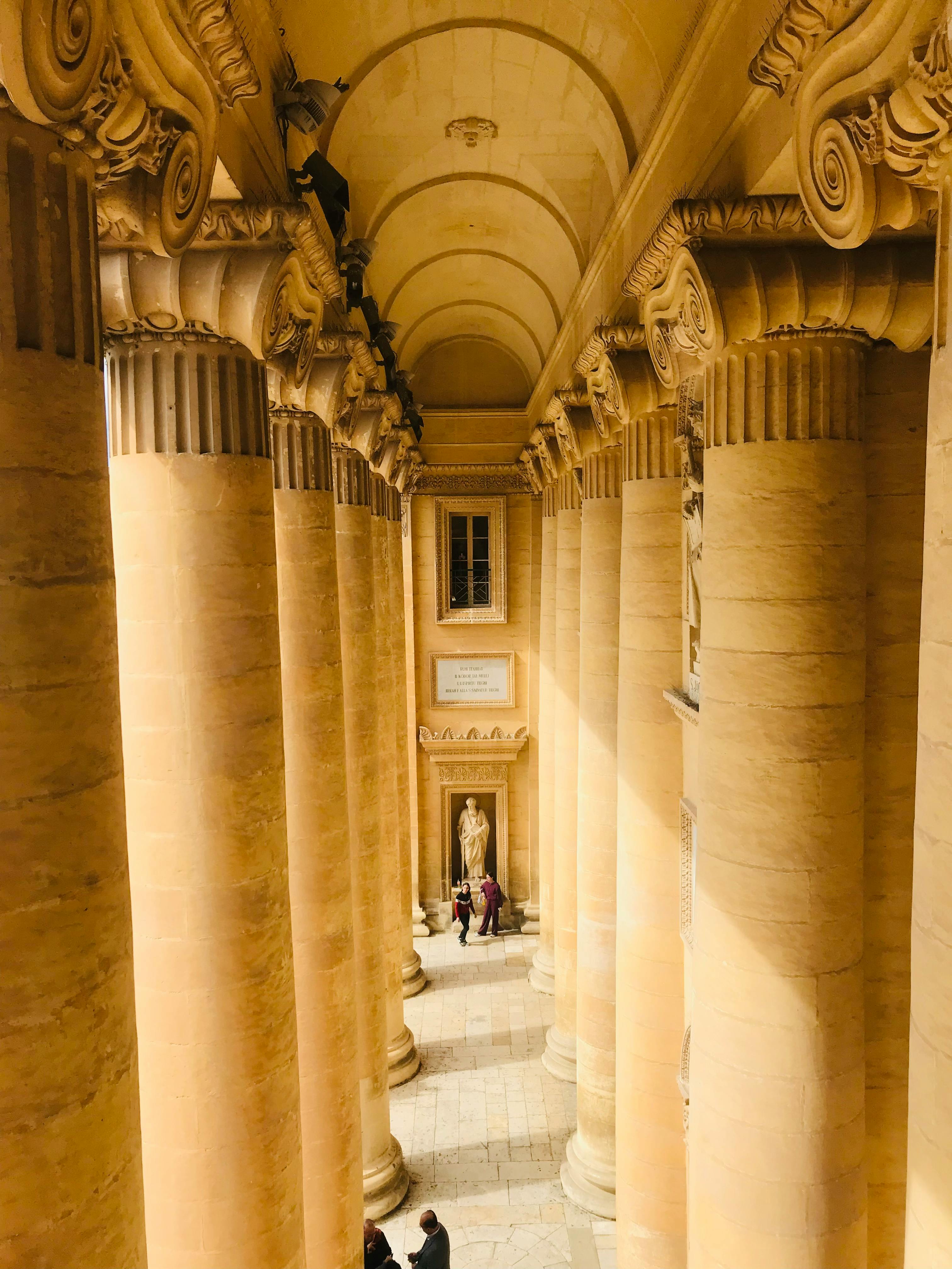 Zadarmo Úžasný výhľad na veľkolepé architektonické stĺpy vo vnútri historickej budovy s elegantným dizajnom a teplými tónmi. Fotka z fotobanky