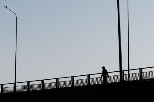 Free Silhouette of a person walking on a bridge against clear sky at twilight. Stock Photo