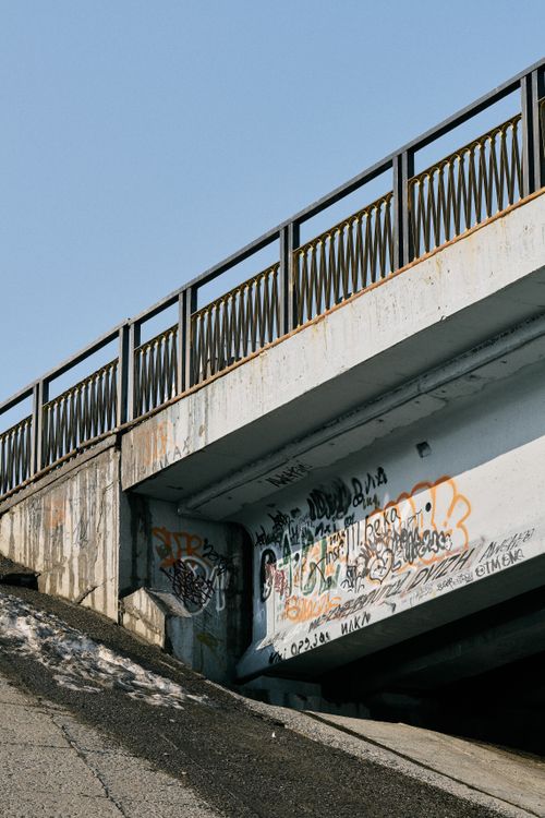 Free A concrete bridge featuring colorful graffiti against a clear blue sky backdrop. Stock Photo