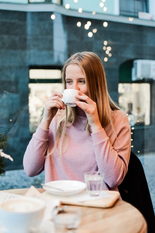Woman in Pink Sweater Drinking from White Ceramic Mug
