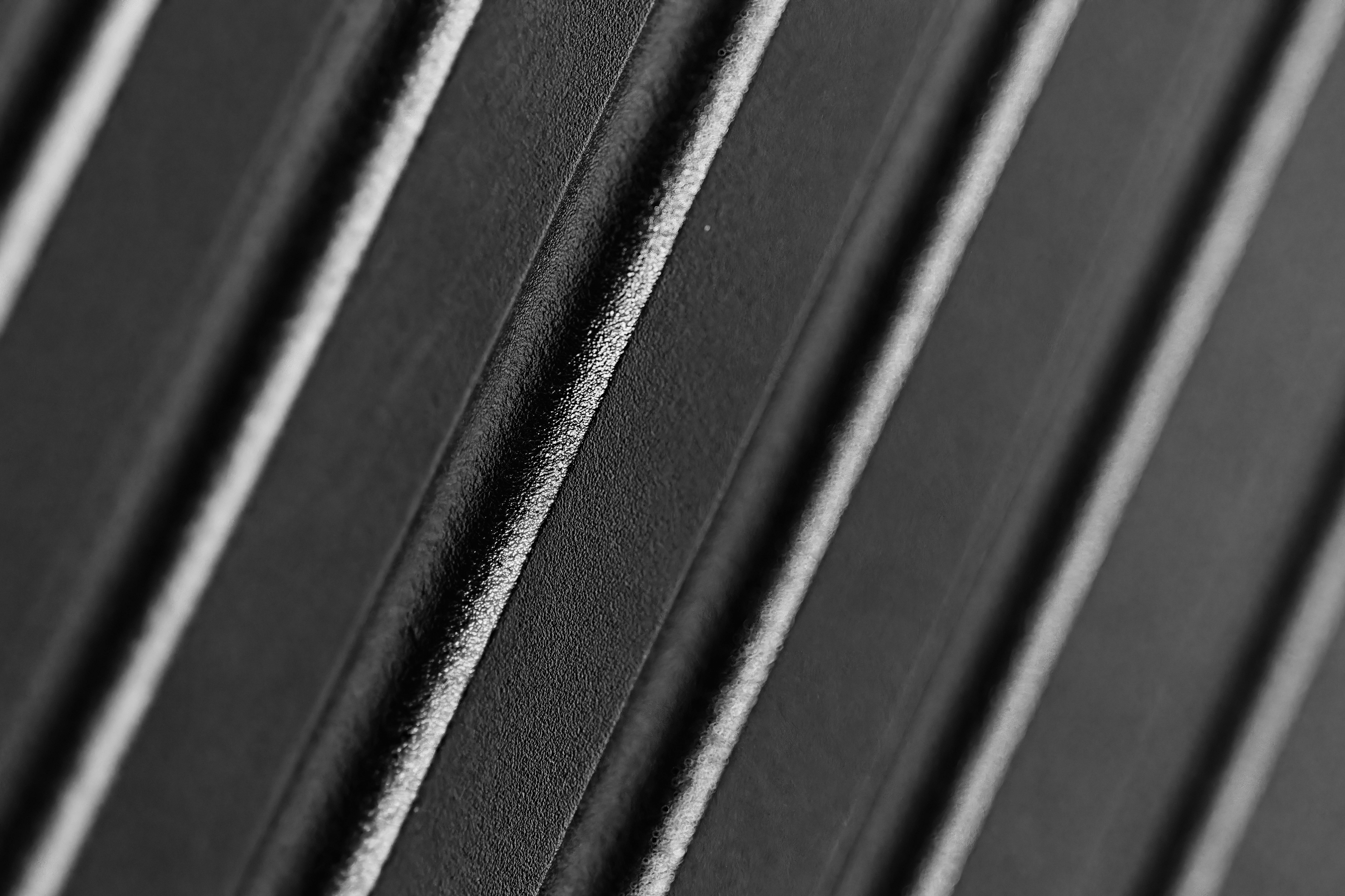 ingyenes Absztrakt makró felvétel egy fekete textúrájú felületről, amely bonyolult átlós vonalakat mutat. Stockfotó