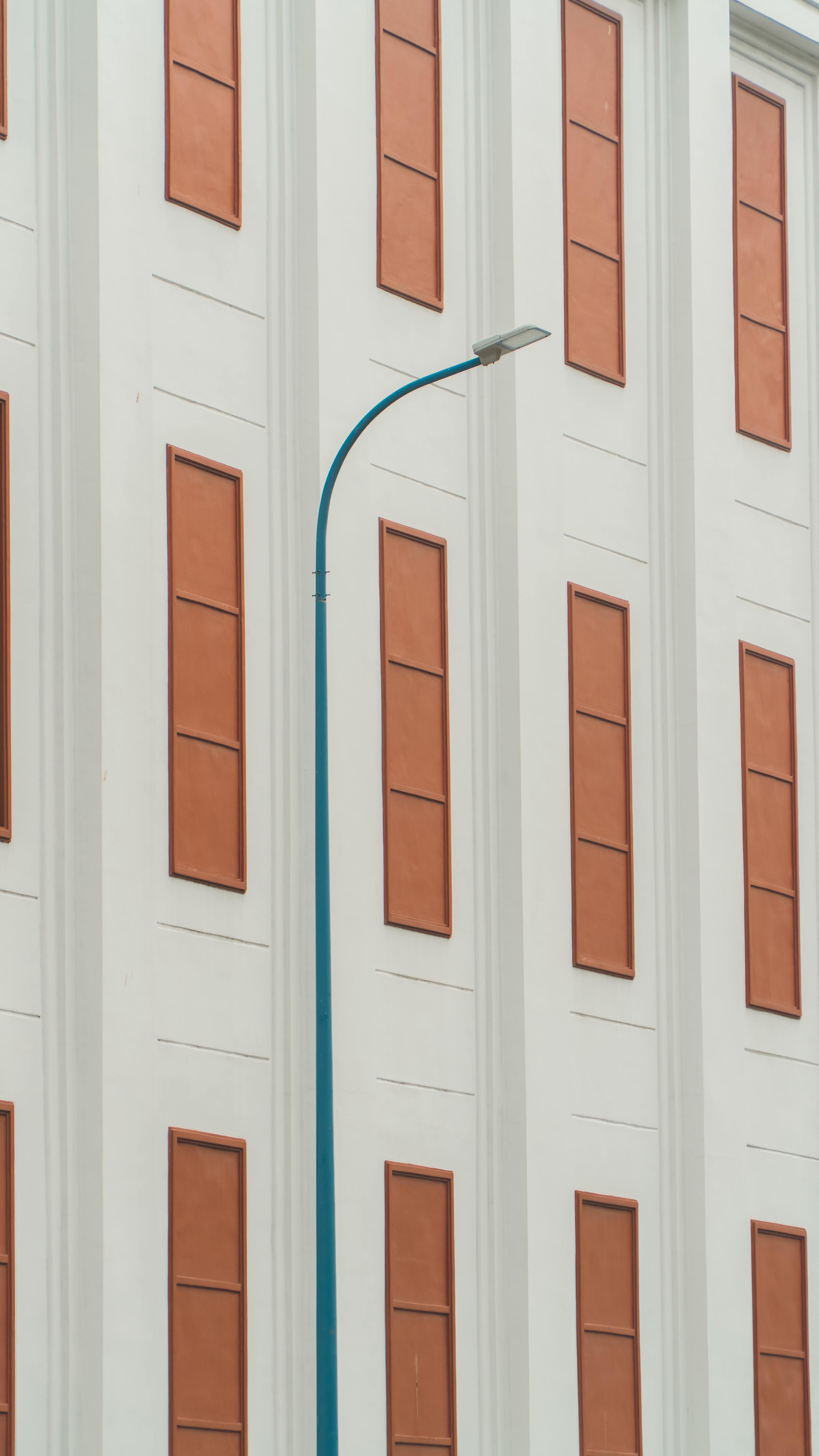 Zadarmo Symetrická fasáda budovy s unikátnou modrou pouličnou lampou vytvára moderný kontrast. Fotka z fotobanky