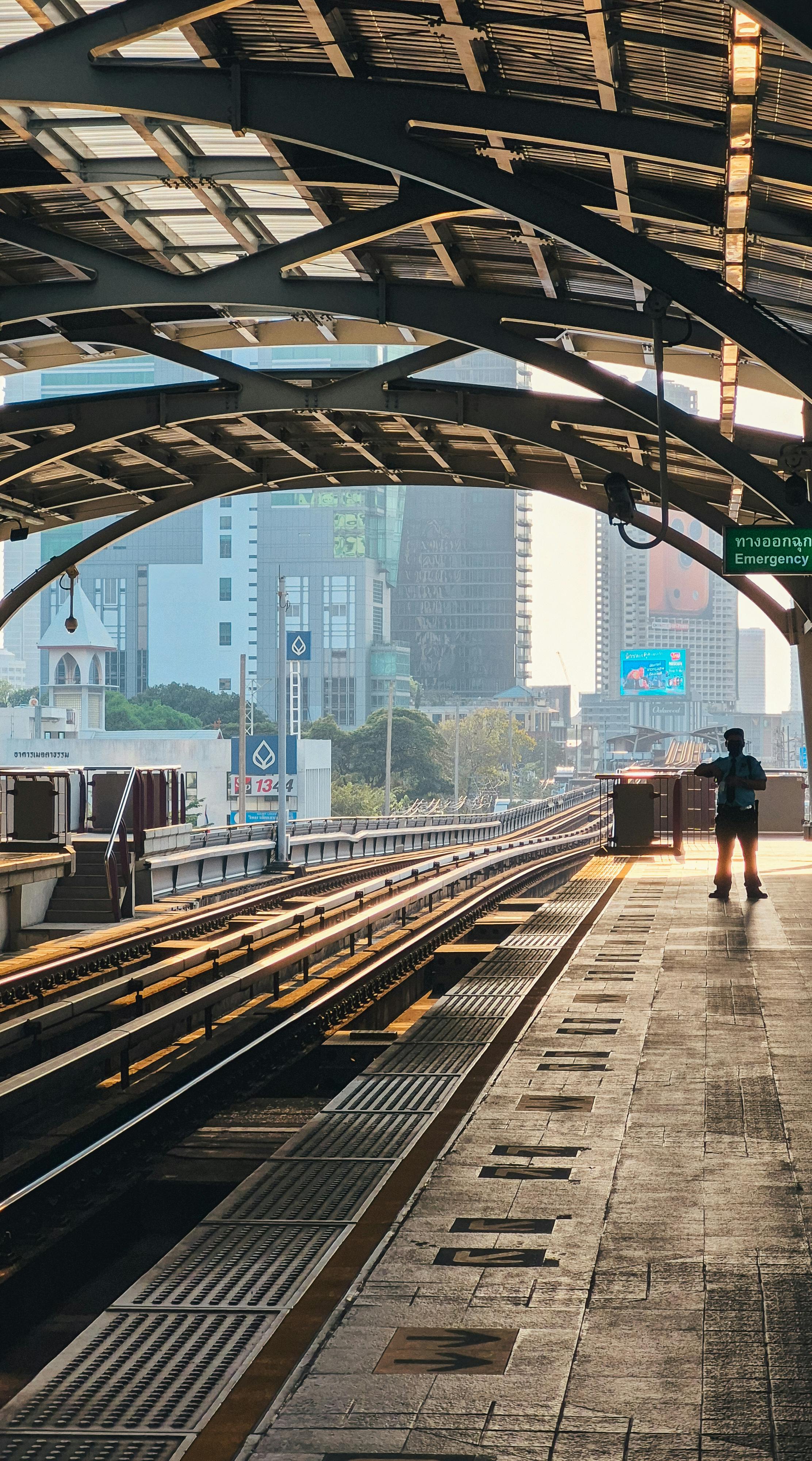 De franc Un passatger espera a una estació de tren de Bangkok a la posta de sol, capturant la vida i l'arquitectura de la ciutat. Foto d'estoc