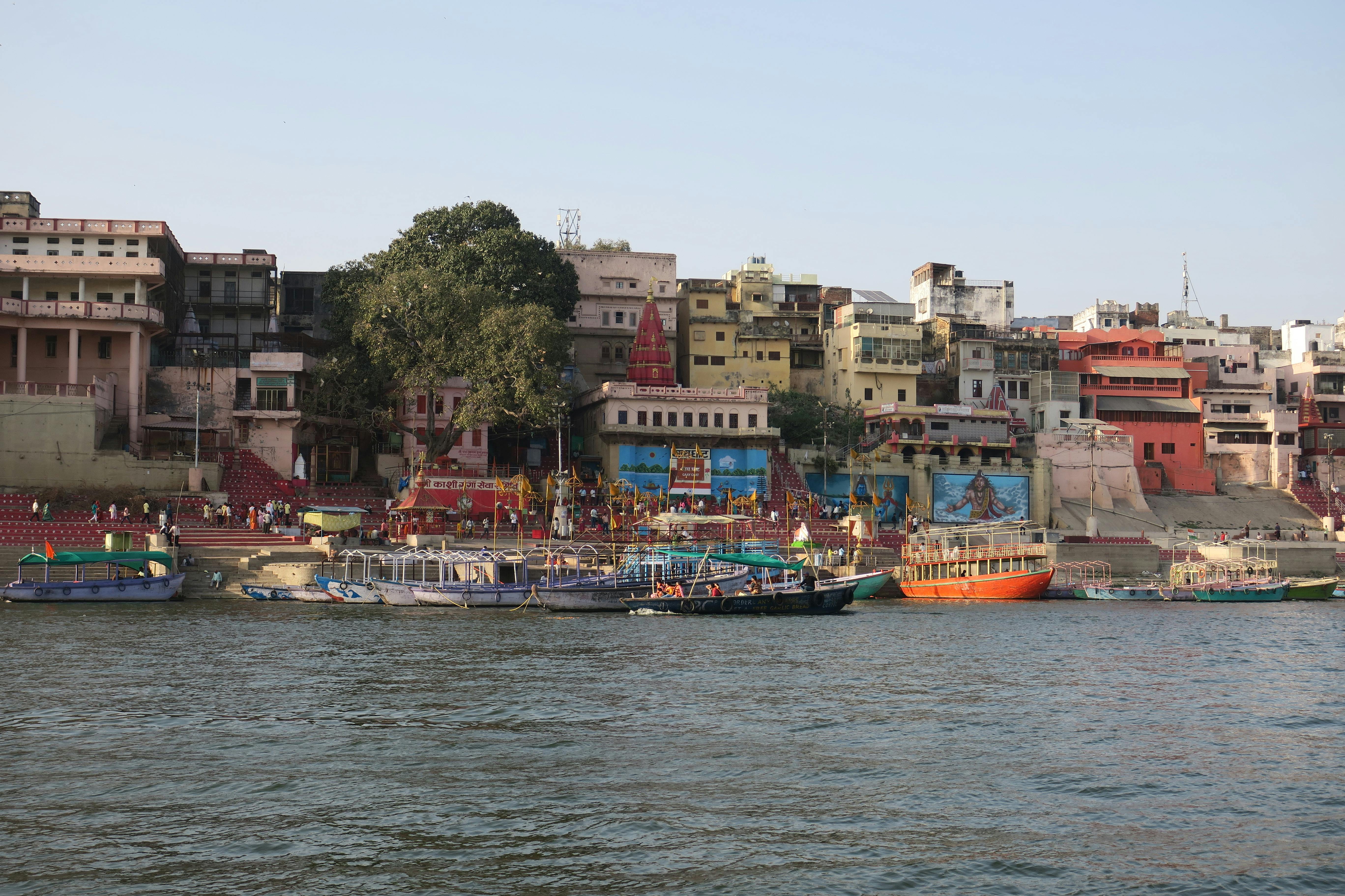 grátis Cena vibrante dos ghats de Varanasi com barcos no rio Ganges, exibindo marcos culturais e históricos. Foto profissional