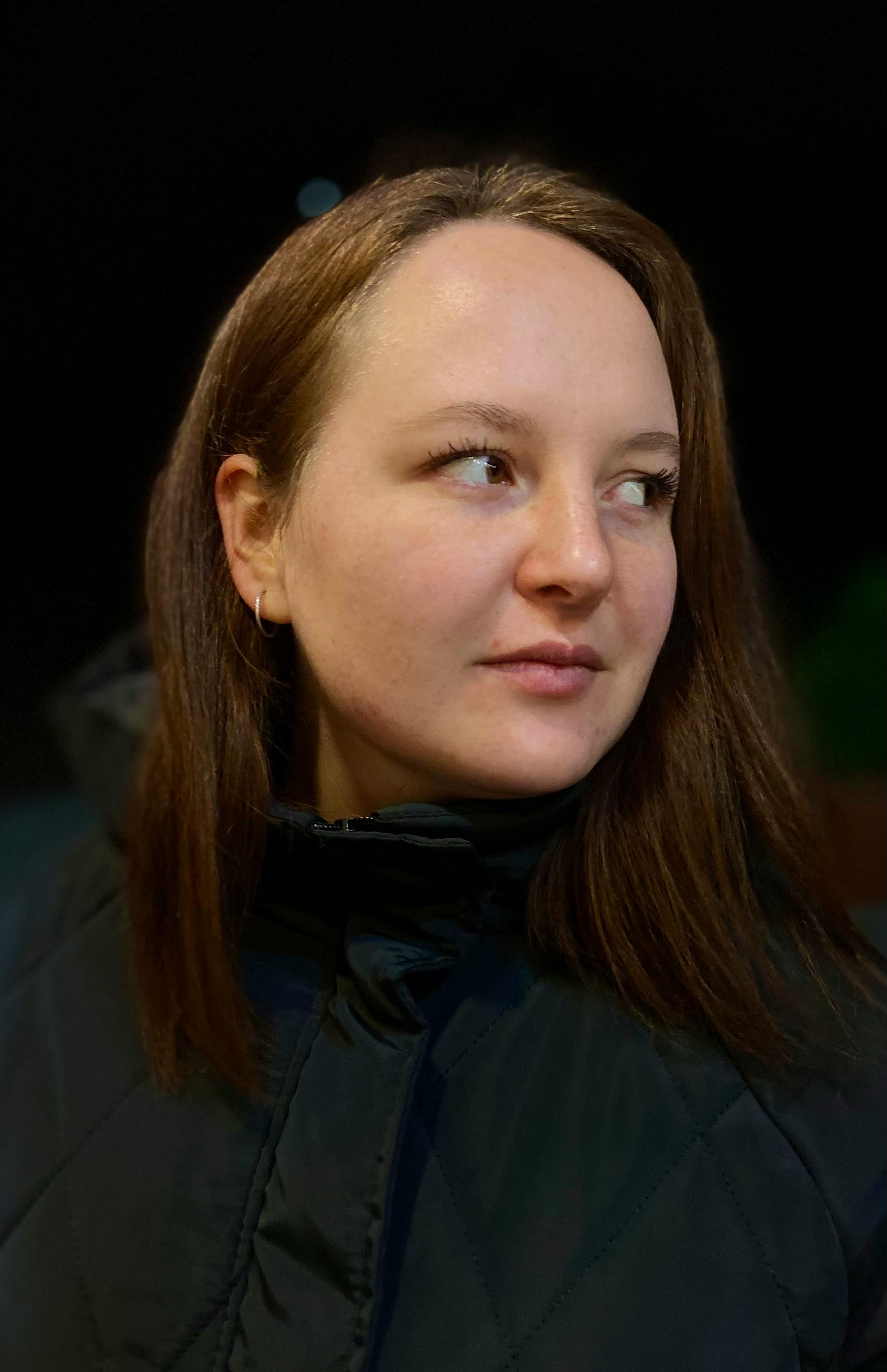 grátis Retrato em close-up de uma mulher ao ar livre à noite, olhando para o lado. Foto profissional