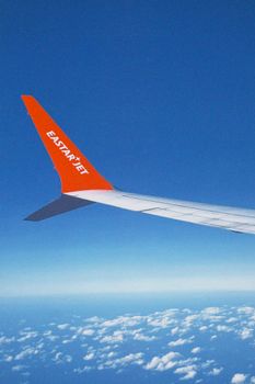 View from airplane with Eastar Jet wingtip over a clear blue sky and ocean.