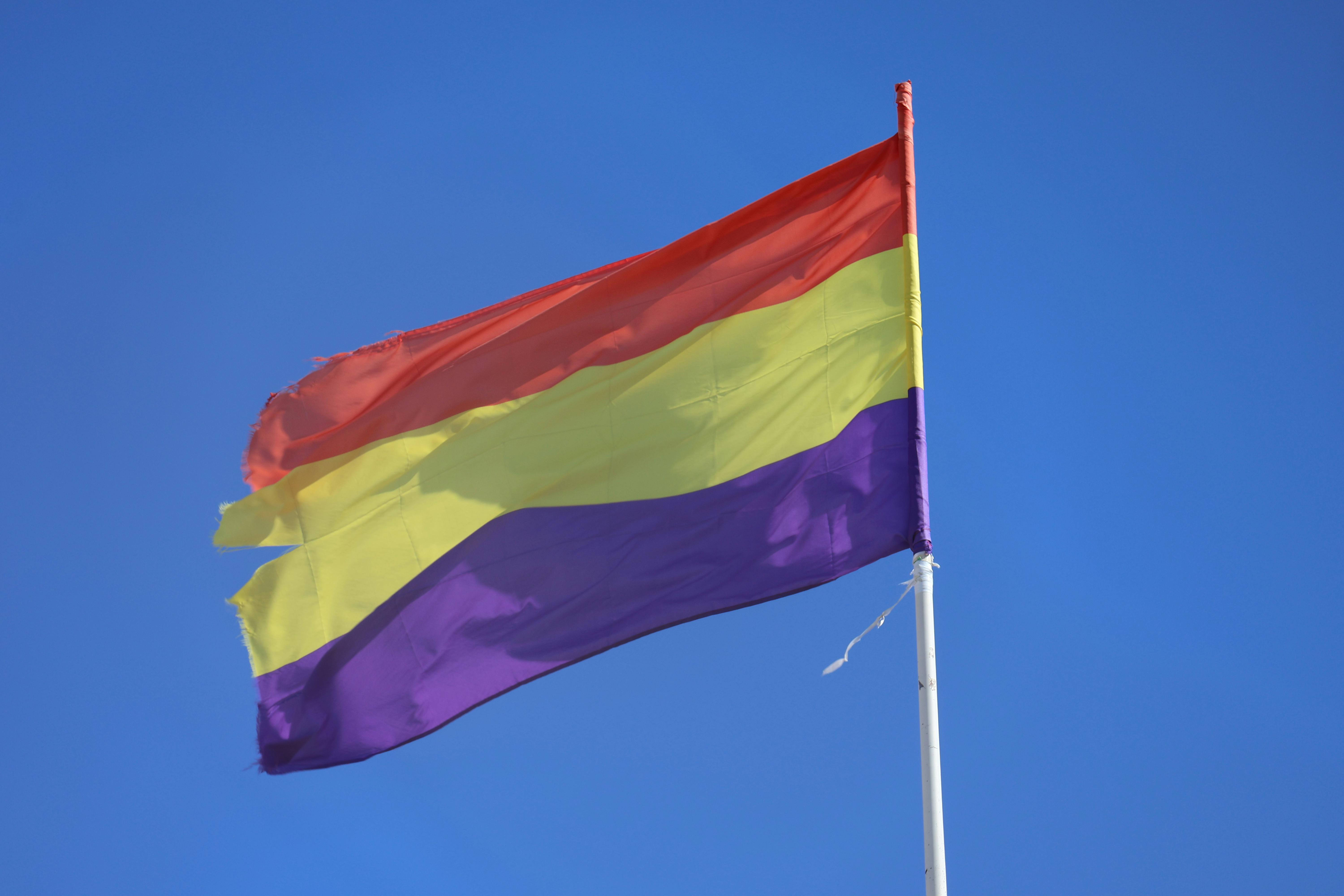 Gratis La vibrante bandiera repubblicana spagnola sventola contro un cielo azzurro e limpido a El Puerto de Santa María. Foto a disposizione