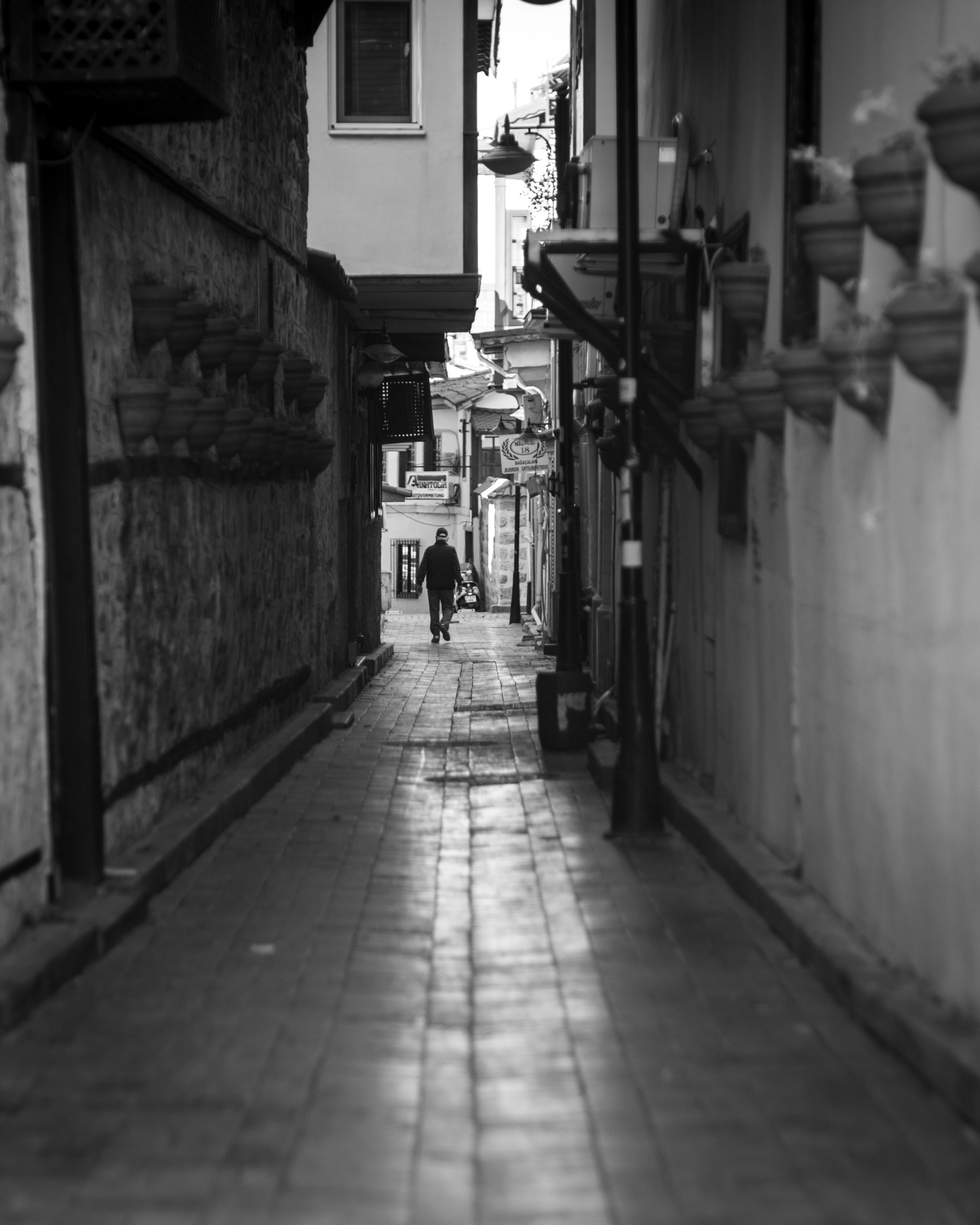 Gratuit O siluetă solitară merge printr-o alee îngustă dintr-un oraș istoric, surprinsă în alb și negru. Fotografie de stoc