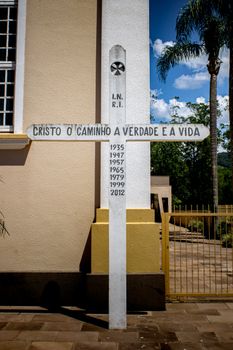A cross monument outside a church in Bom Princípio, Brazil, with a biblical inscription.