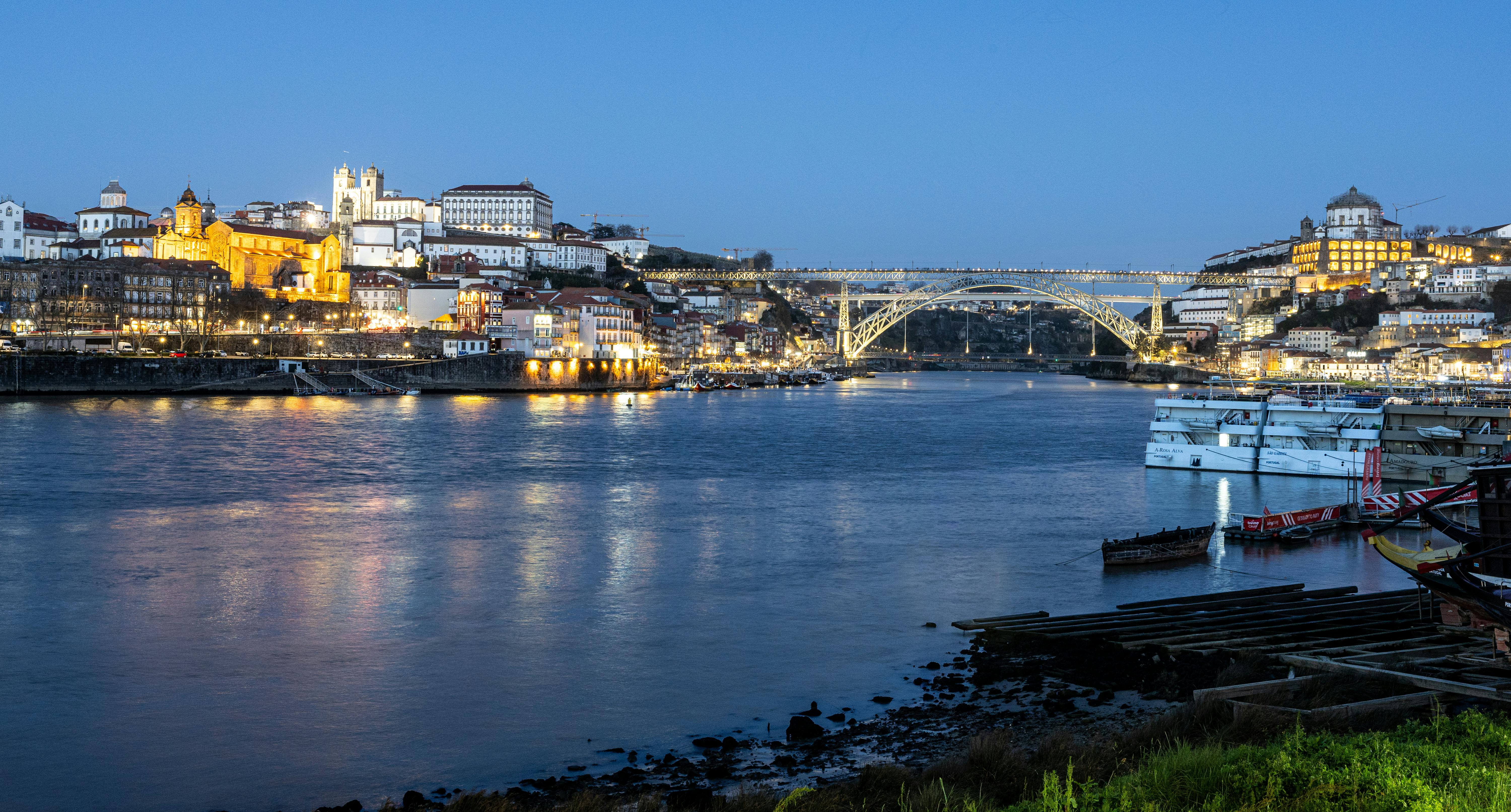 grátis Vista noturna do Porto, Portugal com a Ponte Dom Luís I iluminada que atravessa o Rio Douro. Foto profissional