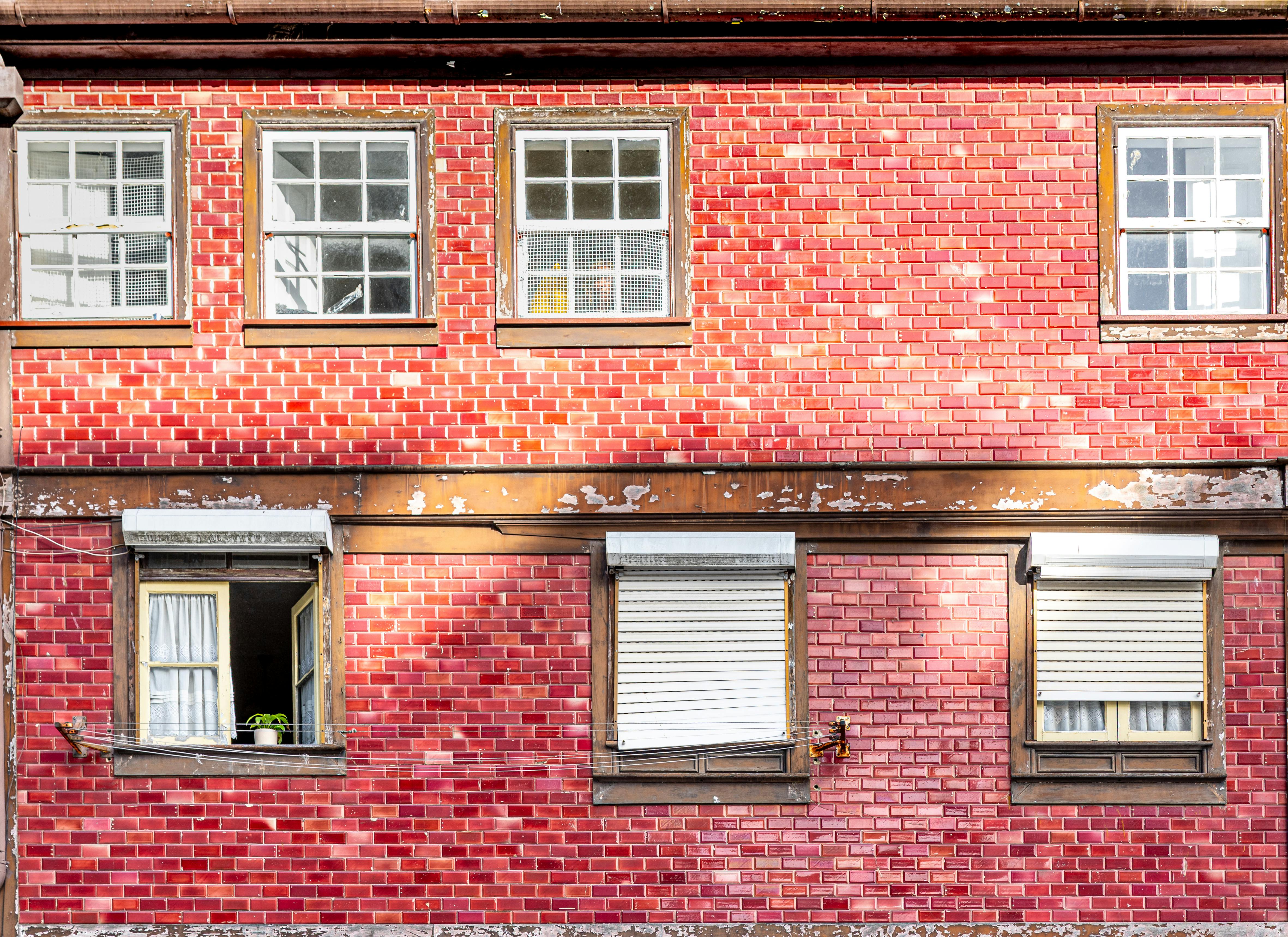 De franc Una façana clàssica d'edifici de maó vermell amb finestres de fusta vintage, que captura l'arquitectura urbana de Porto, Portugal. Foto d'estoc