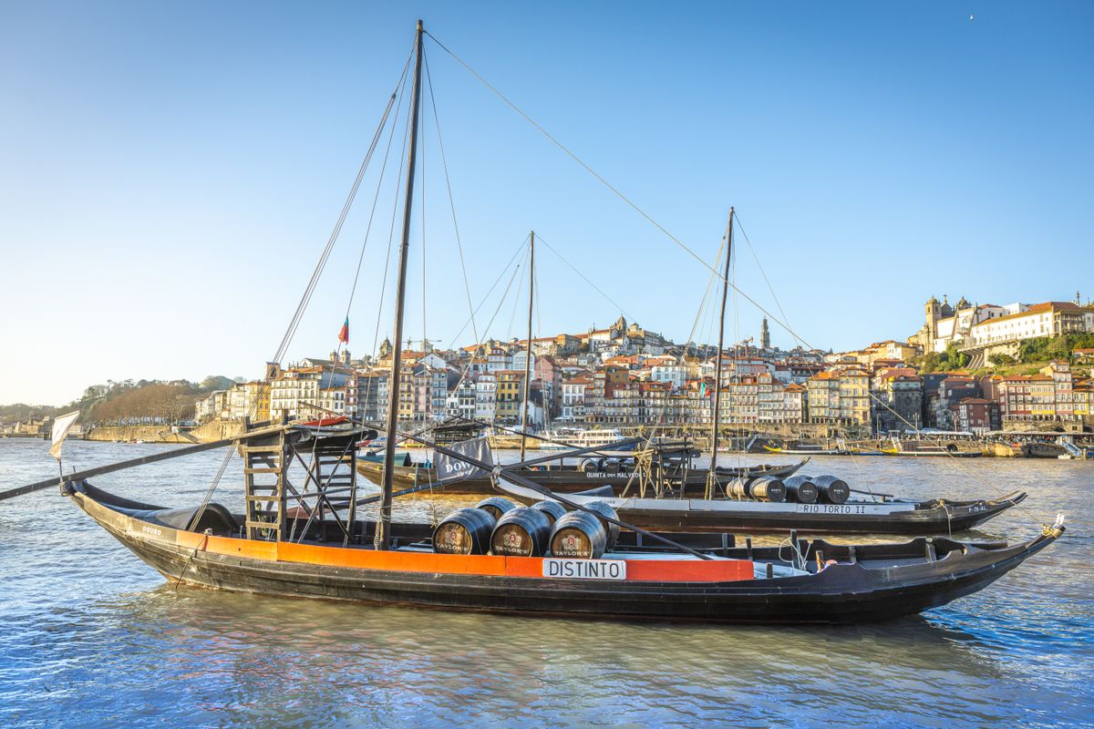 Rabelo boats with wine barrels on the Douro River, Porto showcasing historic waterfront architecture.
