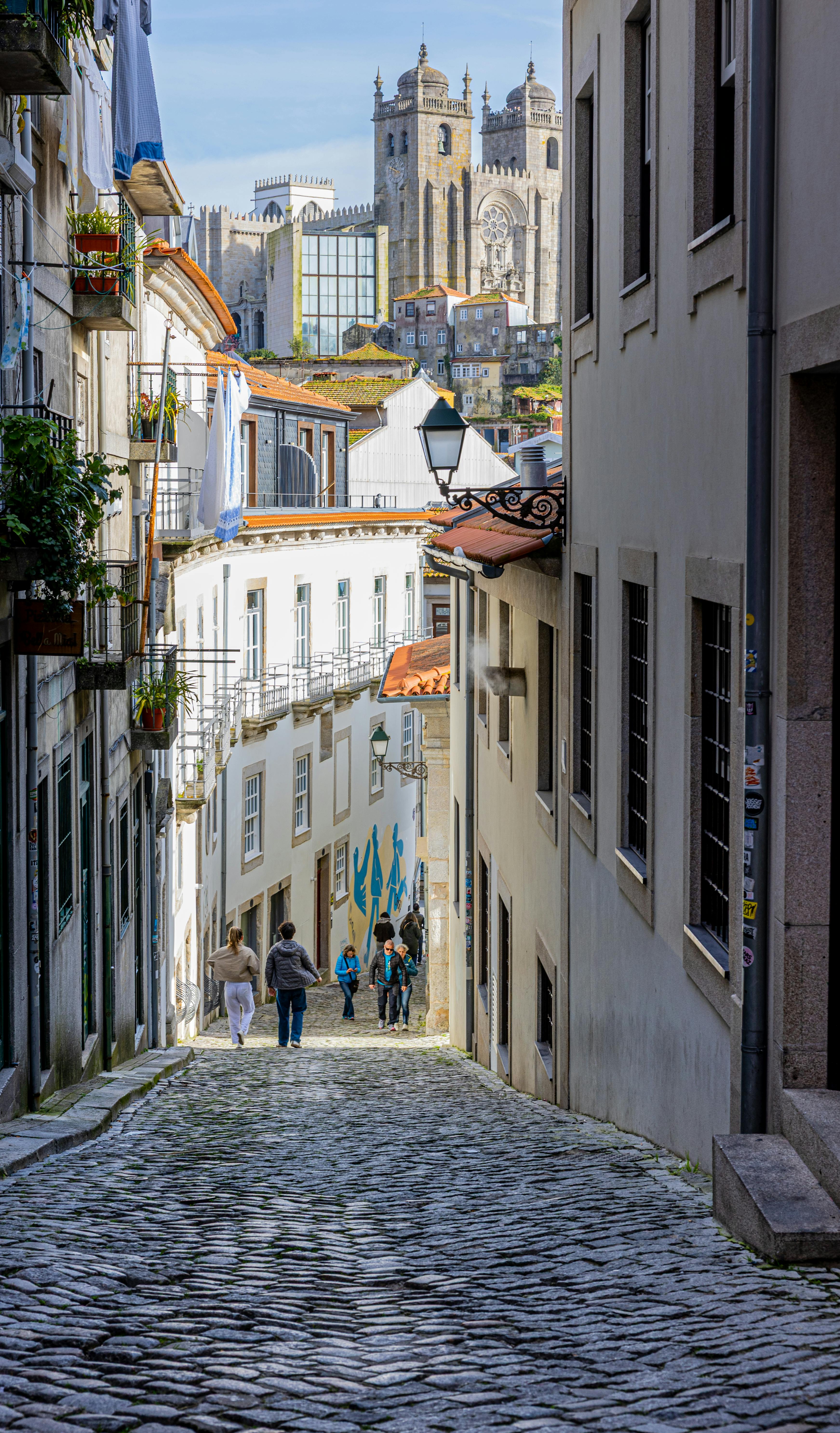 Kostnadsfria Vacker utsikt över en kullerstensgata i Porto, Portugal med Portokatedralen i bakgrunden. Rik på historia och kultur. Stock foto
