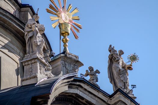 Close-up of intricate religious statues on a historic Italian church facade against blue sky.
