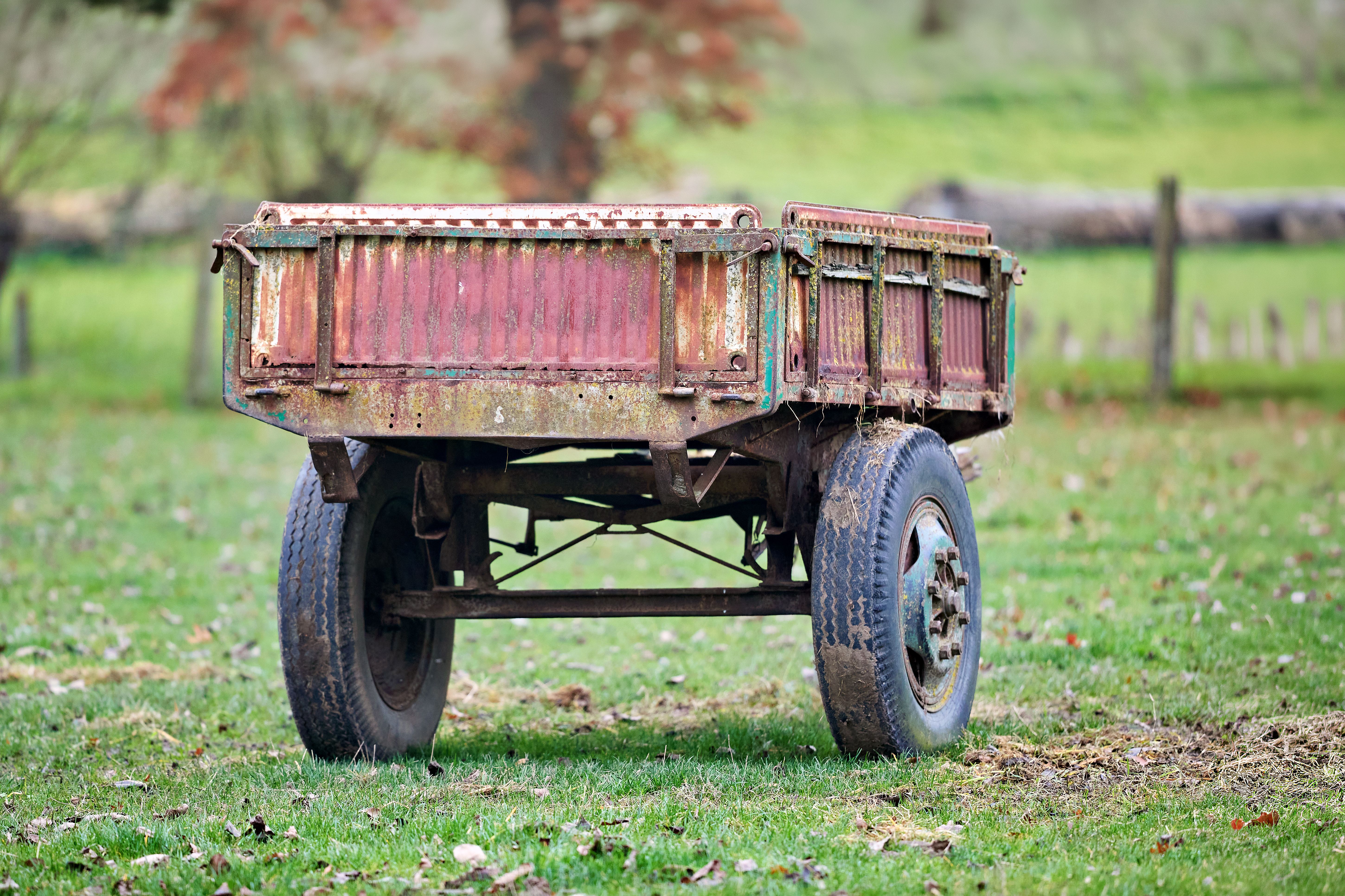 Weathered gooseneck equipment trailer with rotted deck parked in a Faulkner County field