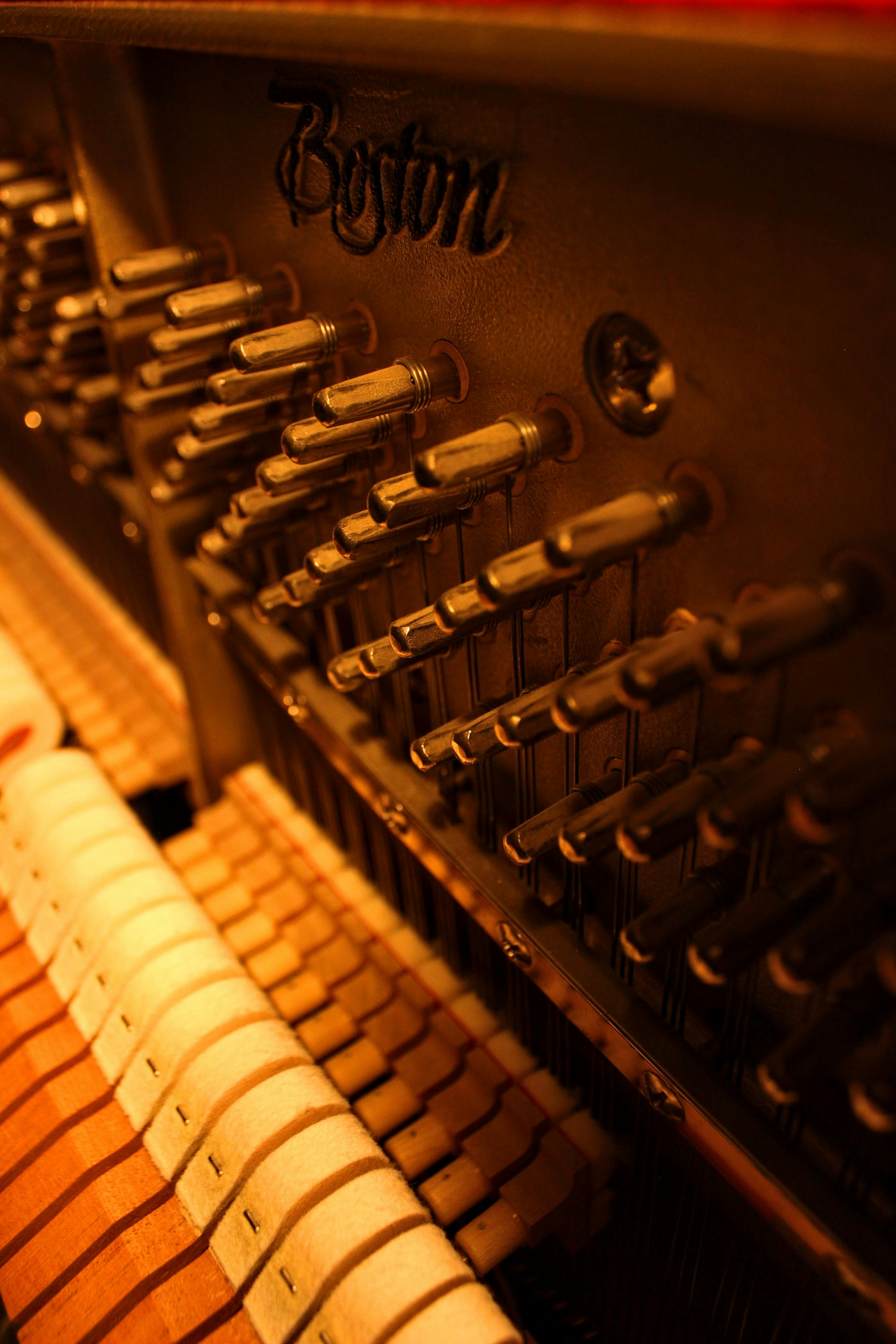 免費 鋼琴內部細節圖，在溫暖的燈光下清晰可見調音釘和琴弦。 圖庫相片