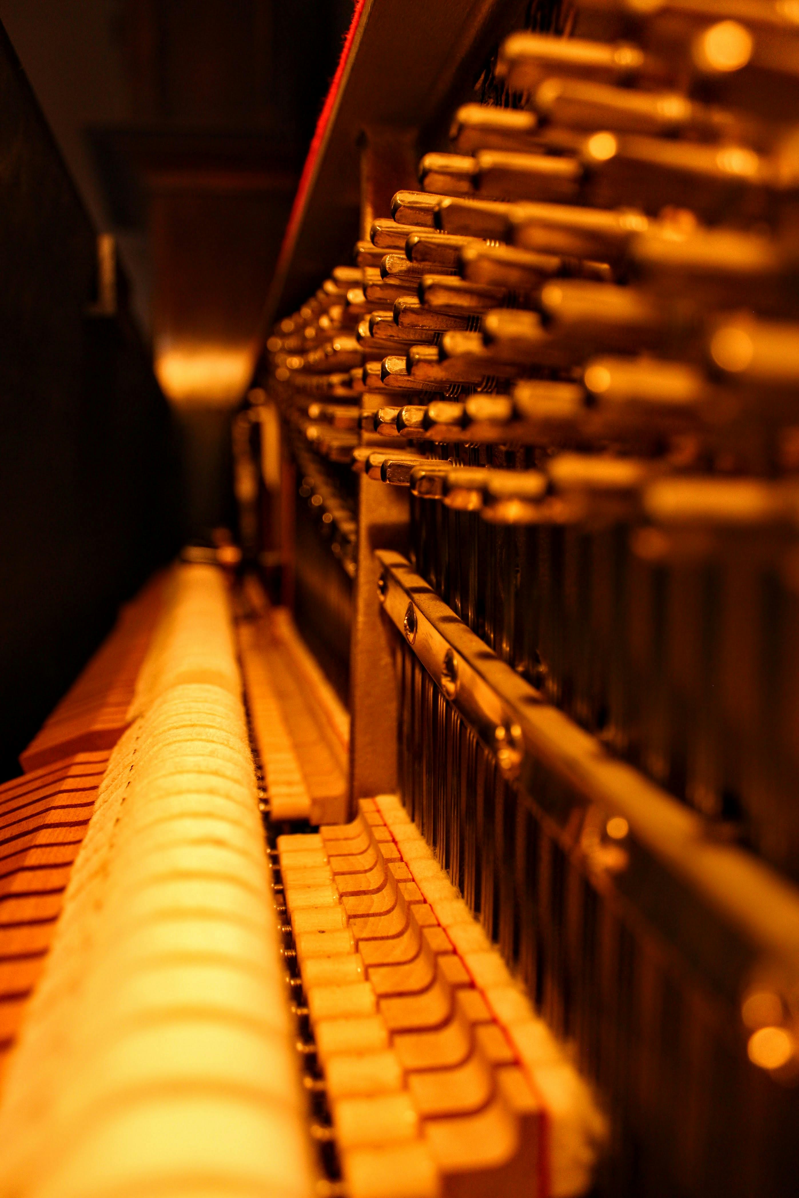 ฟรี ภาพแสดงรายละเอียดการทำงานภายในของเปียโน เผยให้เห็นกลไกต่างๆ ภายใต้แสงสีโทนอบอุ่น คลังภาพถ่าย