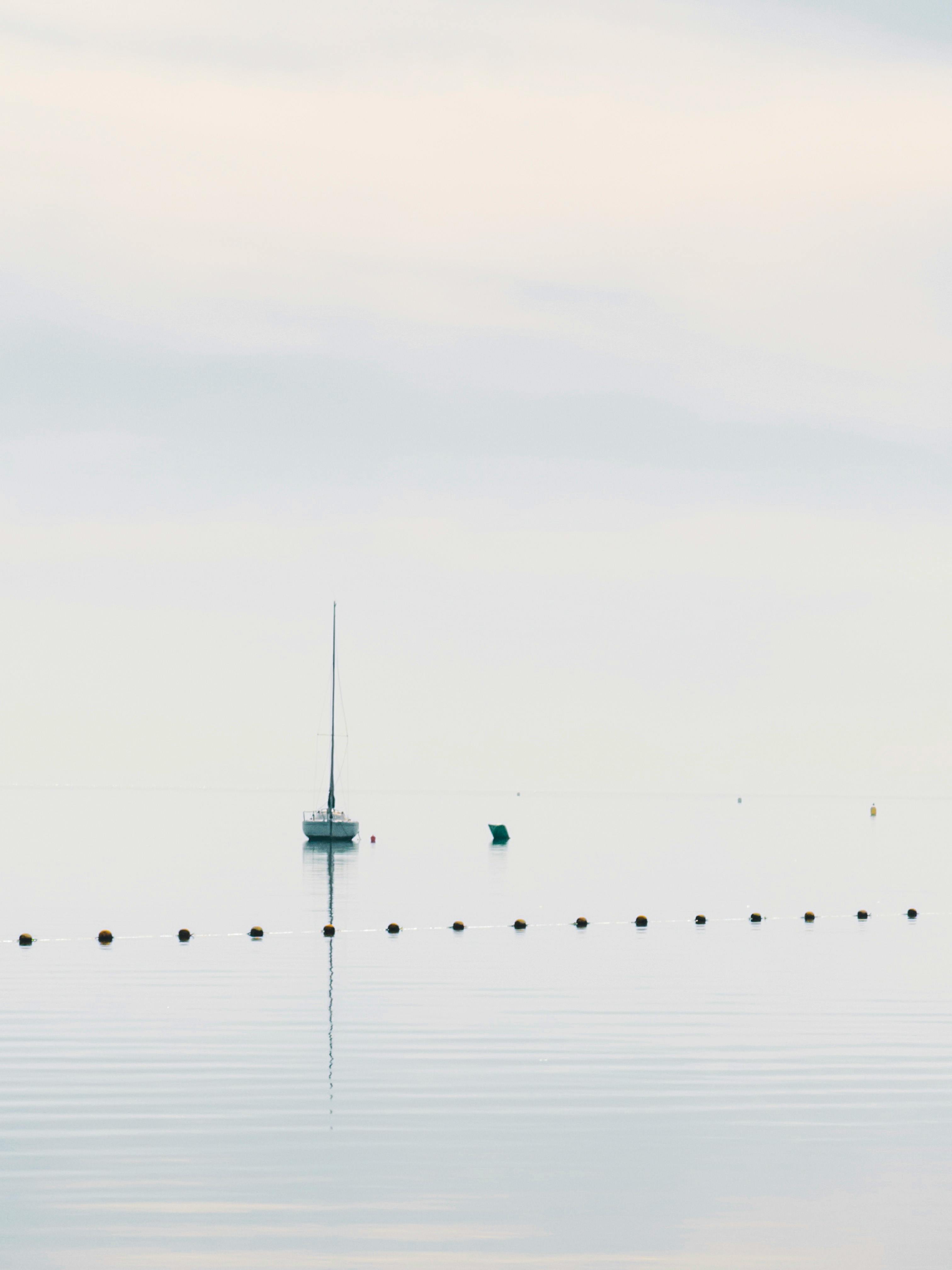 ingyenes Egy vitorlás nyugodt jelenete a nyugodt tengeren naplemente közben, békés és meditatív látványt nyújtva. Stockfotó