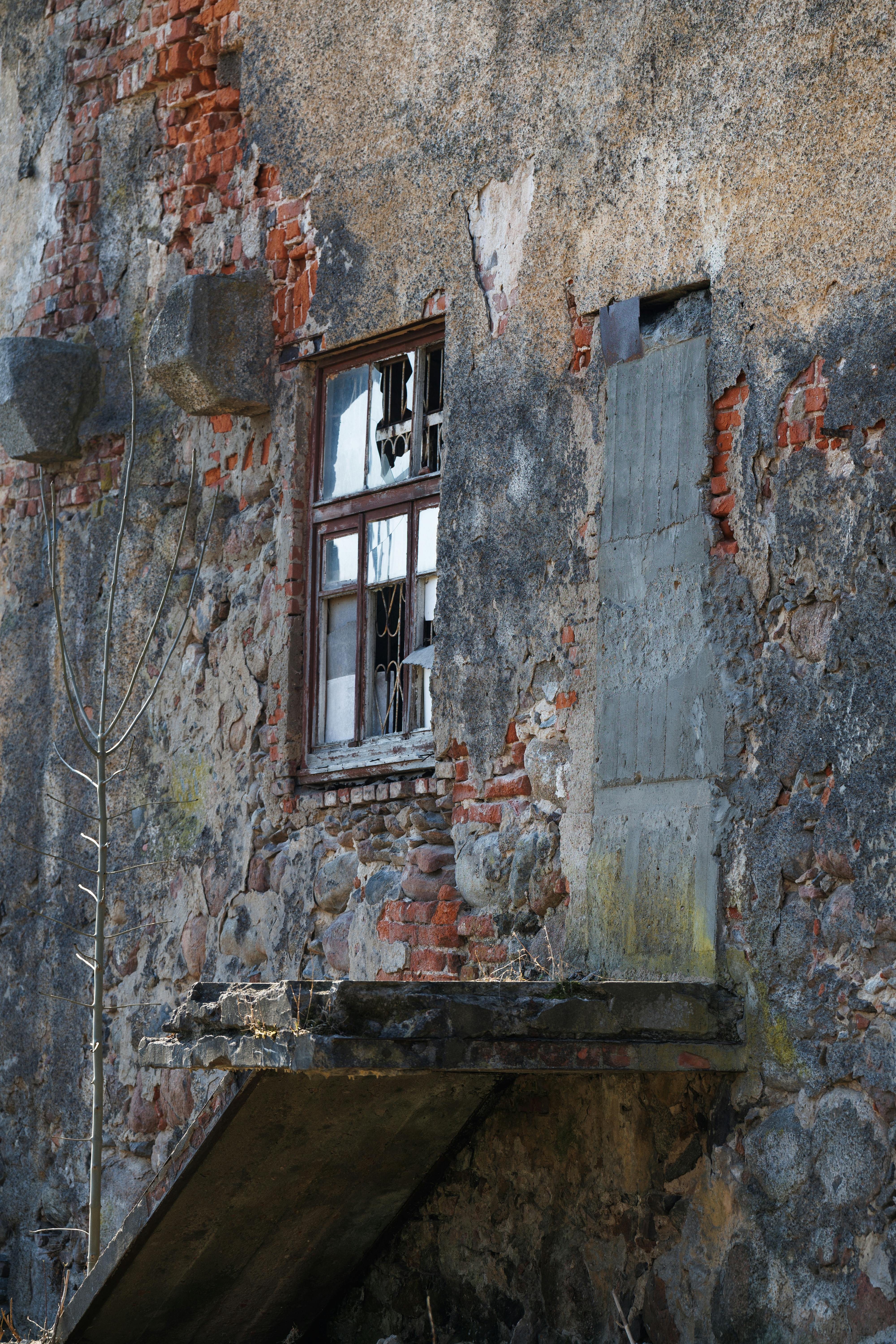 De franc Una paret de pedra rústica amb una finestra trencada, que mostra l'edat i la deterioració. Foto d'estoc