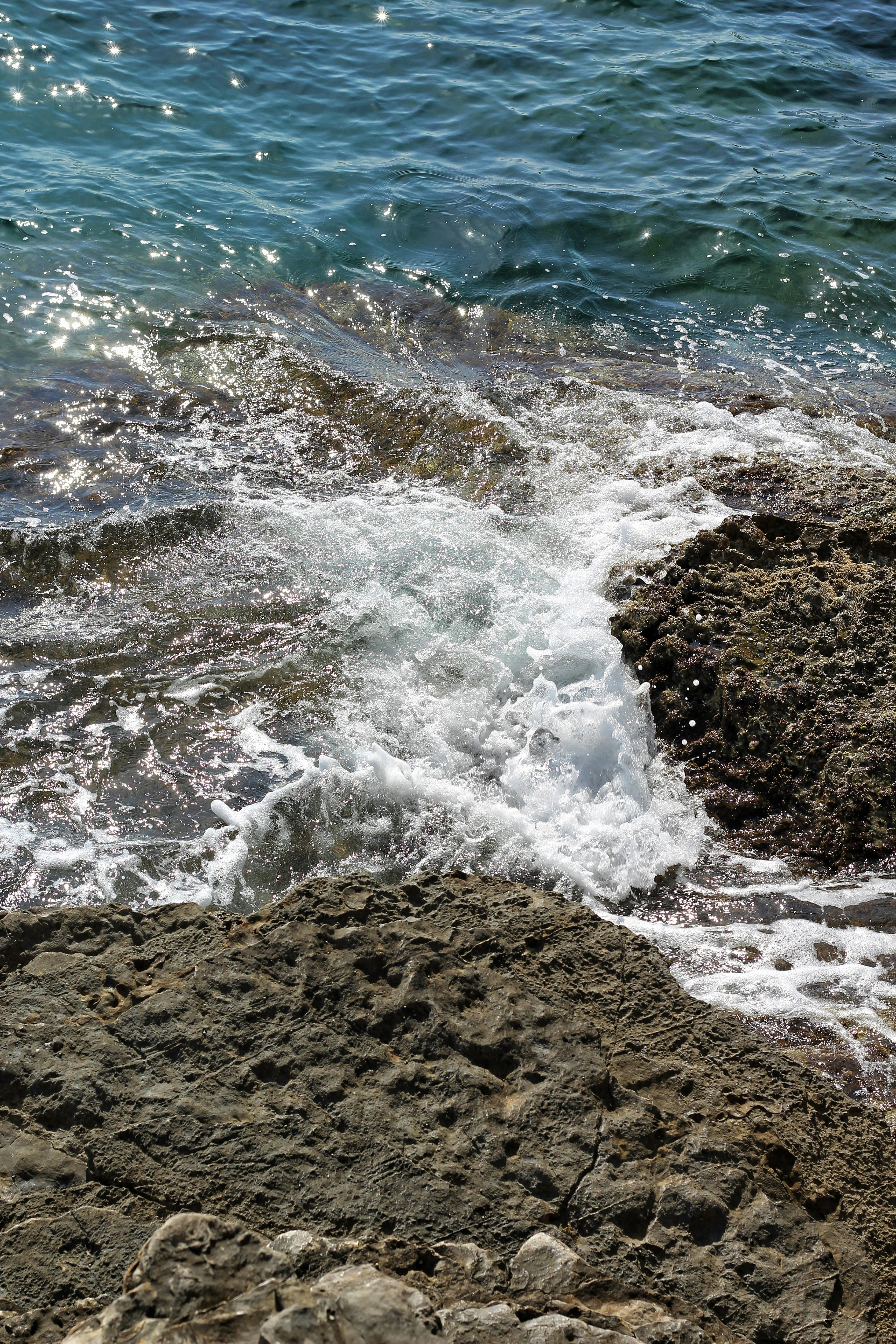 Kostenlos Lebendige Darstellung von Meereswellen, die auf eine felsige Küste treffen und die rohe Kraft und Schönheit der Natur hervorheben. Stock-Foto