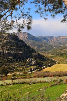 Scenic view of a lush valley with mountains in the backdrop, capturing spring's vibrant hues.