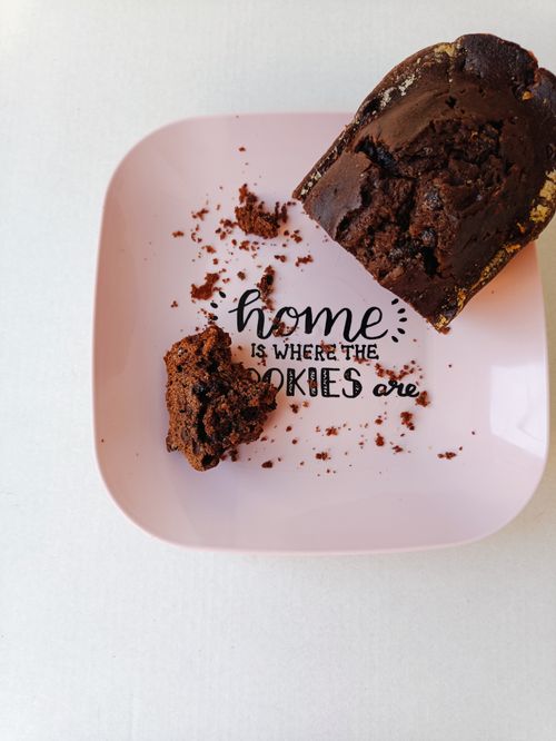 Free A close-up of a chocolate cake slice on a pink plate with crumbs and a witty quote. Stock Photo