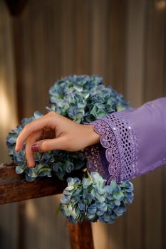 Close-up of a delicate embroidered sleeve touching vibrant hydrangea blooms.