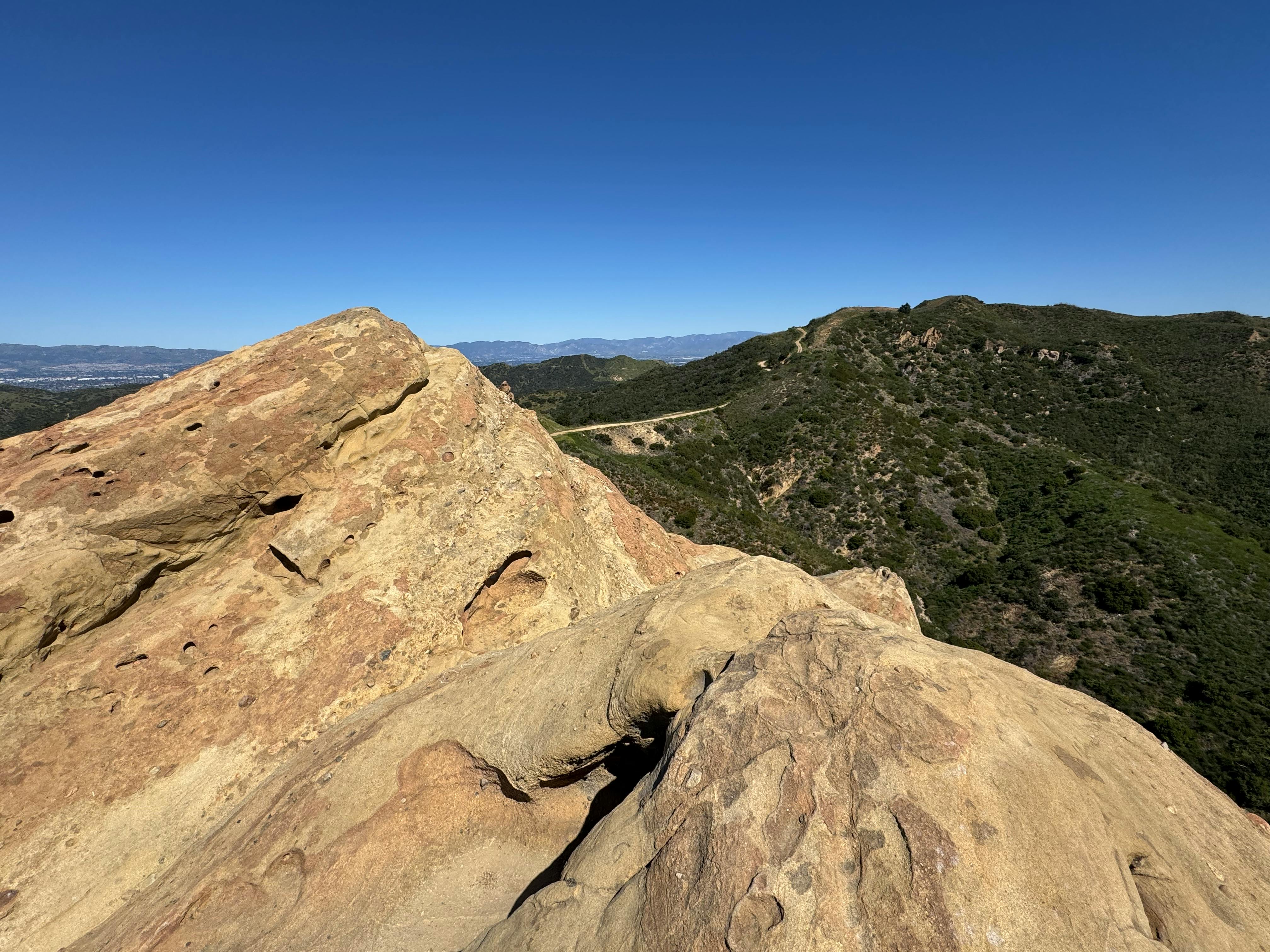 Bezpłatne Rozległy górski krajobraz w Malibu, ukazujący surowe formacje skalne i bujną zieleń pod czystym, błękitnym niebem. Zdjęcie z galerii