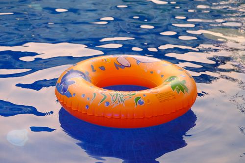 Free A vibrant orange inflatable ring floating in a shimmering blue swimming pool in Bengaluru, India. Stock Photo