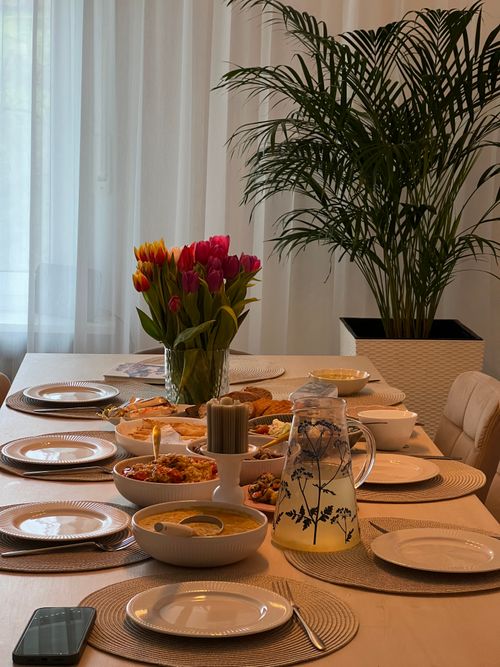 Free Beautifully set indoor dining table with tulips, ready for a gathering. Includes plates, food, and a jug of lemonade. Stock Photo
