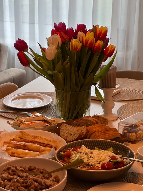 Free A beautifully set dining table with vibrant tulips and an assortment of appetizers ready for a meal. Stock Photo