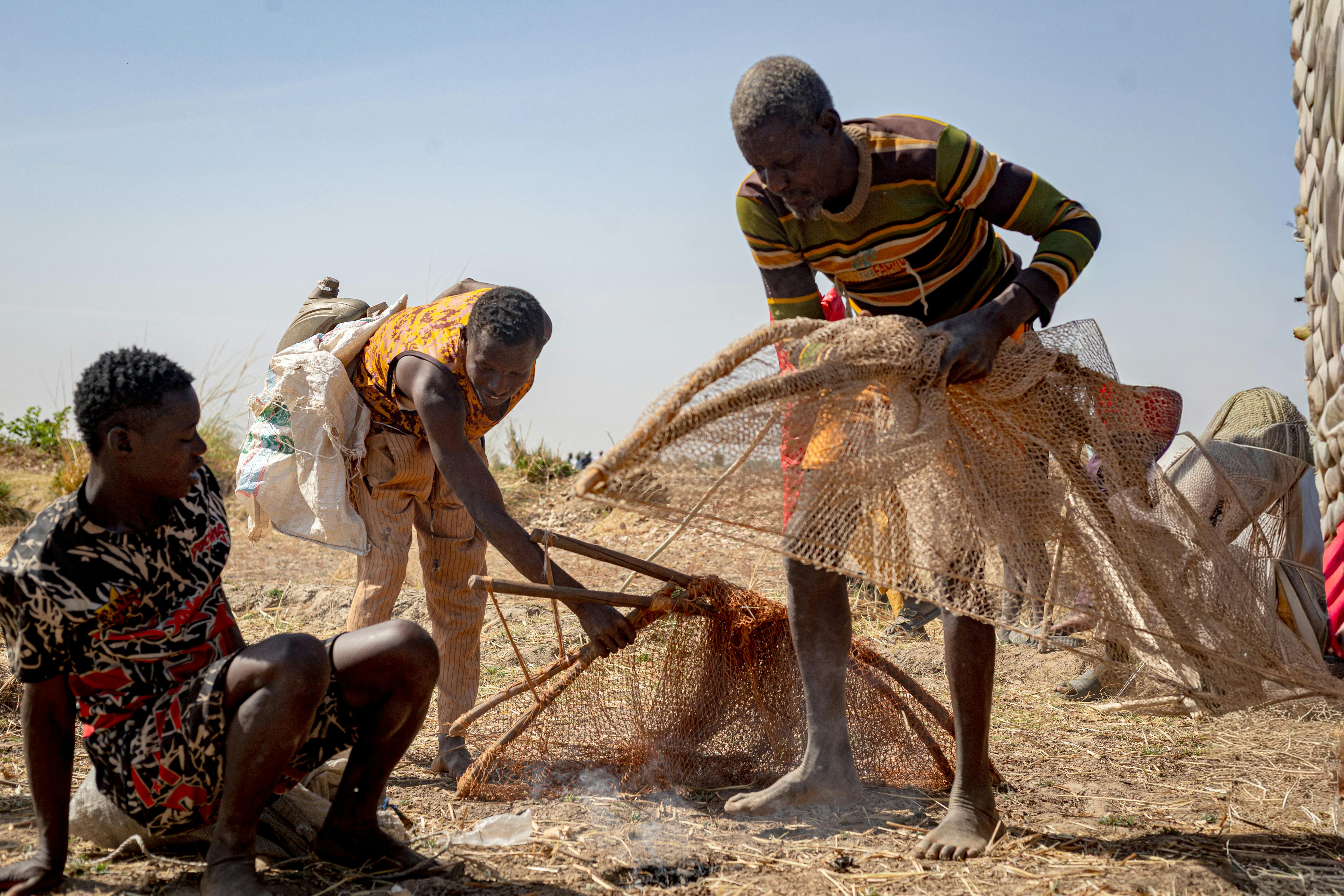 bezplatná Skupina afrických rybářů pracuje v týmu a opravuje sítě za slunečného dne. Základová fotografie