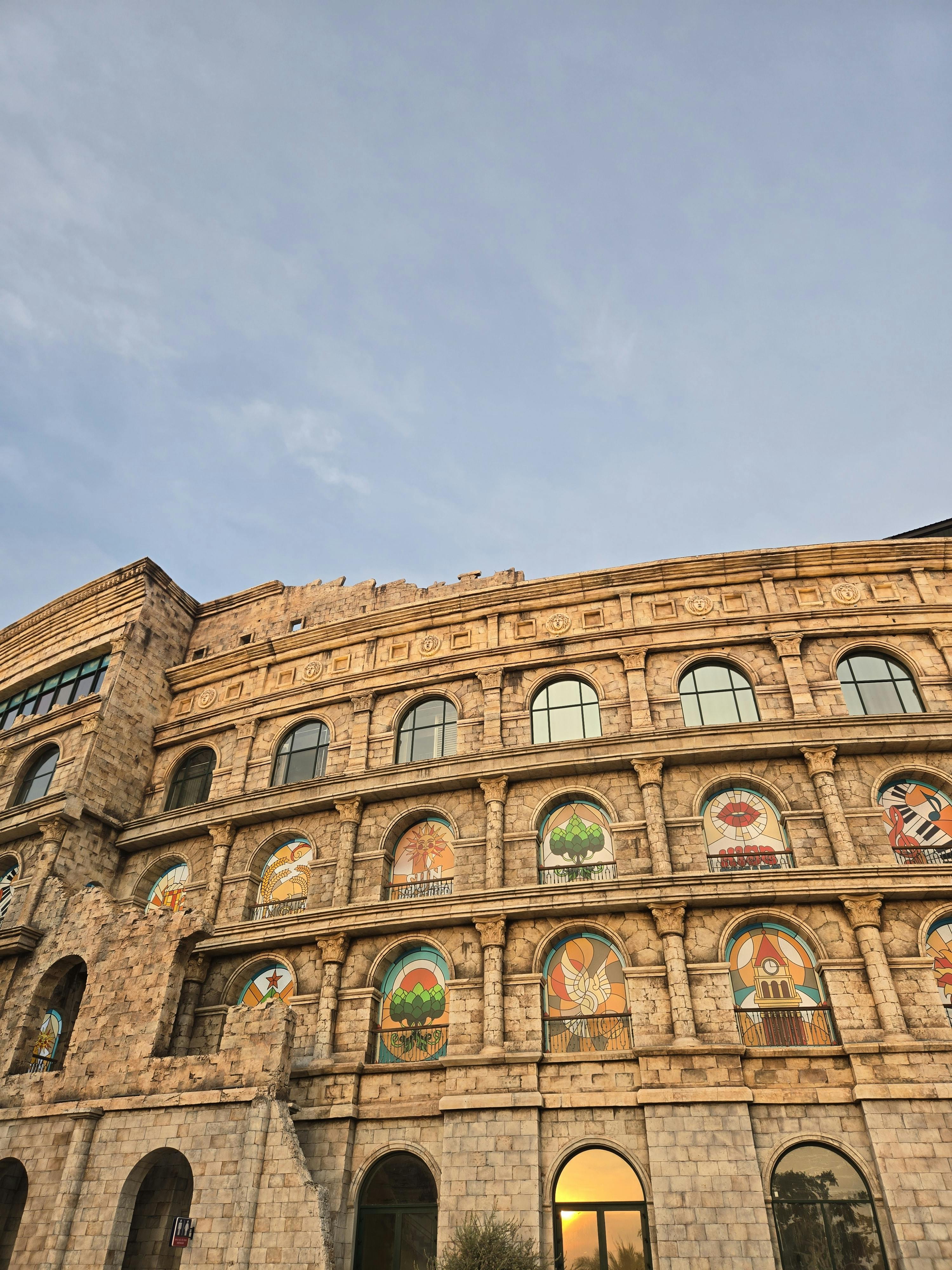 Gratis Majestuoso edificio de piedra con murales artísticos, bajo un vibrante cielo de amanecer. Foto de stock