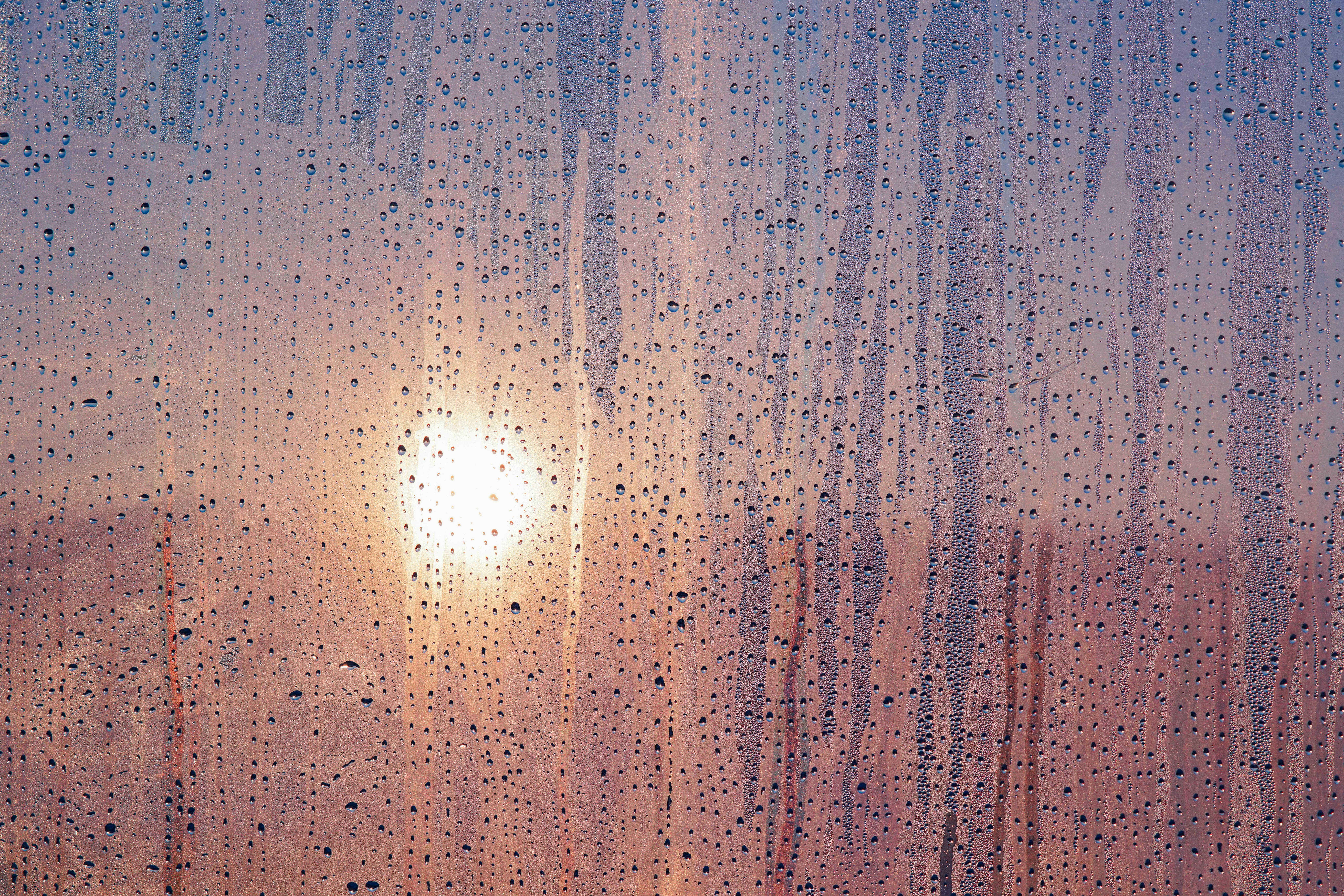 grátis Um belo pôr do sol visto através de uma janela, com gotas de chuva, criando uma atmosfera melancólica. Foto profissional