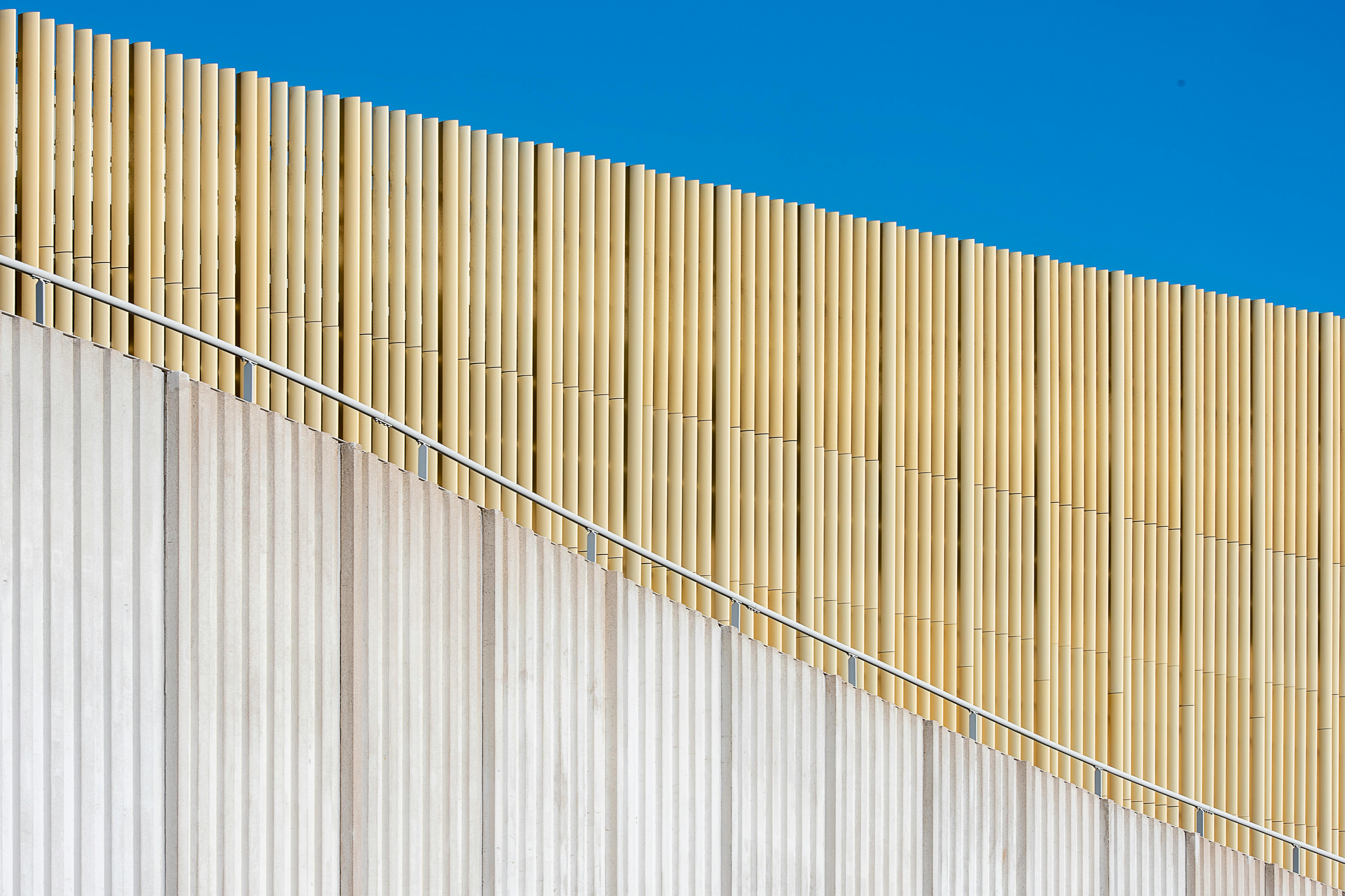 Zadarmo Minimalistická architektonická fasáda s drevenými lamelami pod jasne modrou oblohou. Fotka z fotobanky