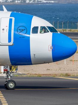 Detailed view of a commercial airplane's cockpit and fuselage on a runway in Spain.