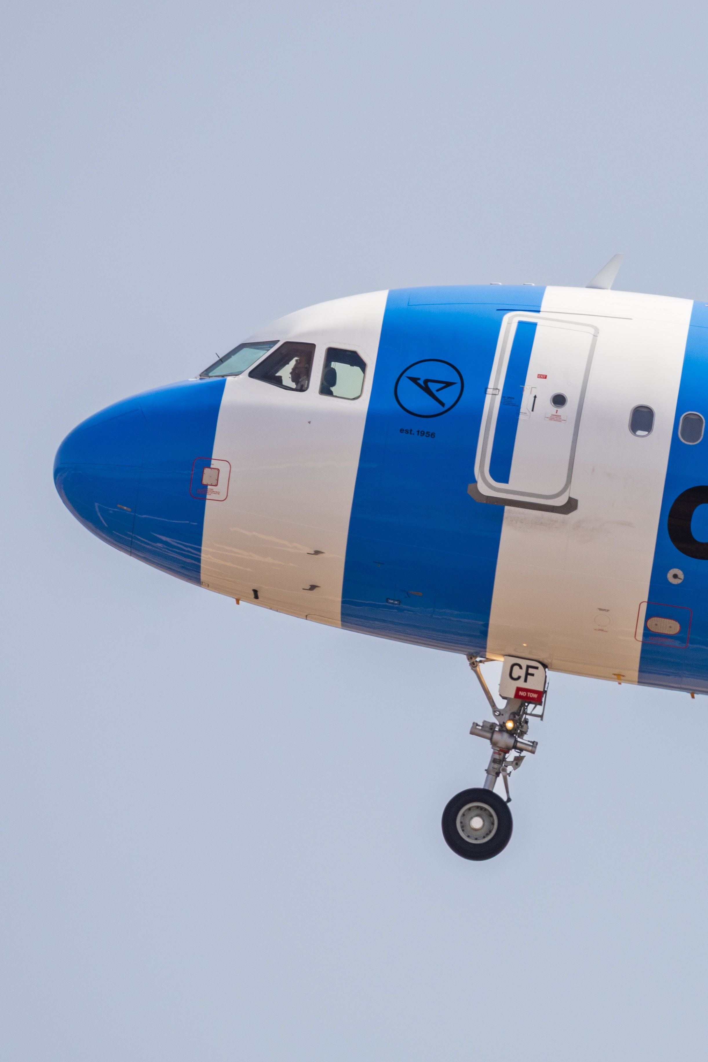 Close-up of an airplane's cockpit and landing gear against a clear blue sky.