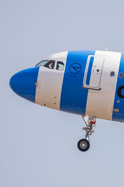 Close-up of an airplane's cockpit and landing gear against a clear blue sky.