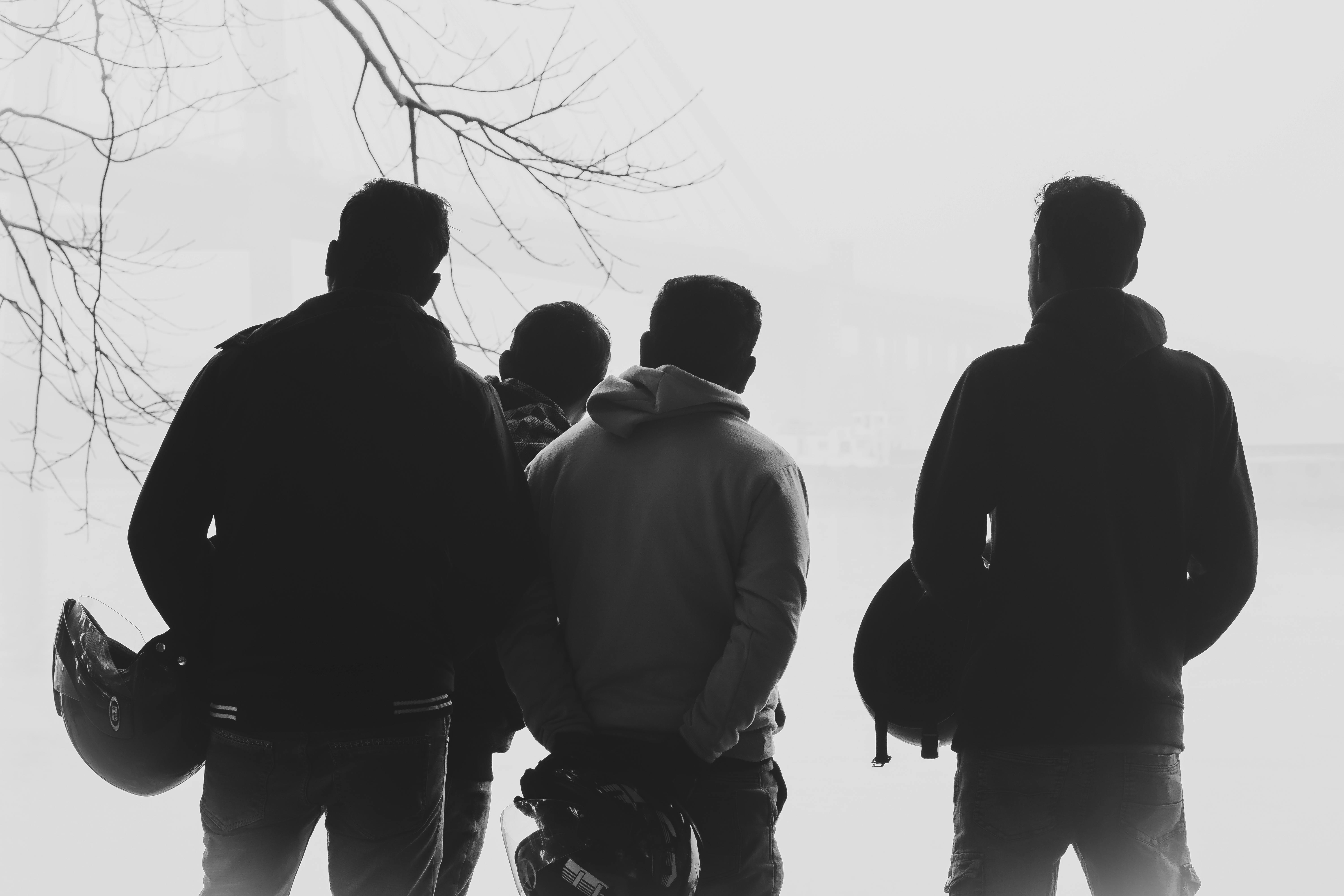 gratis Vier mannen met helmen staan ​​in een mistige buitenomgeving, wat doet denken aan een motoravontuur. Stockfoto