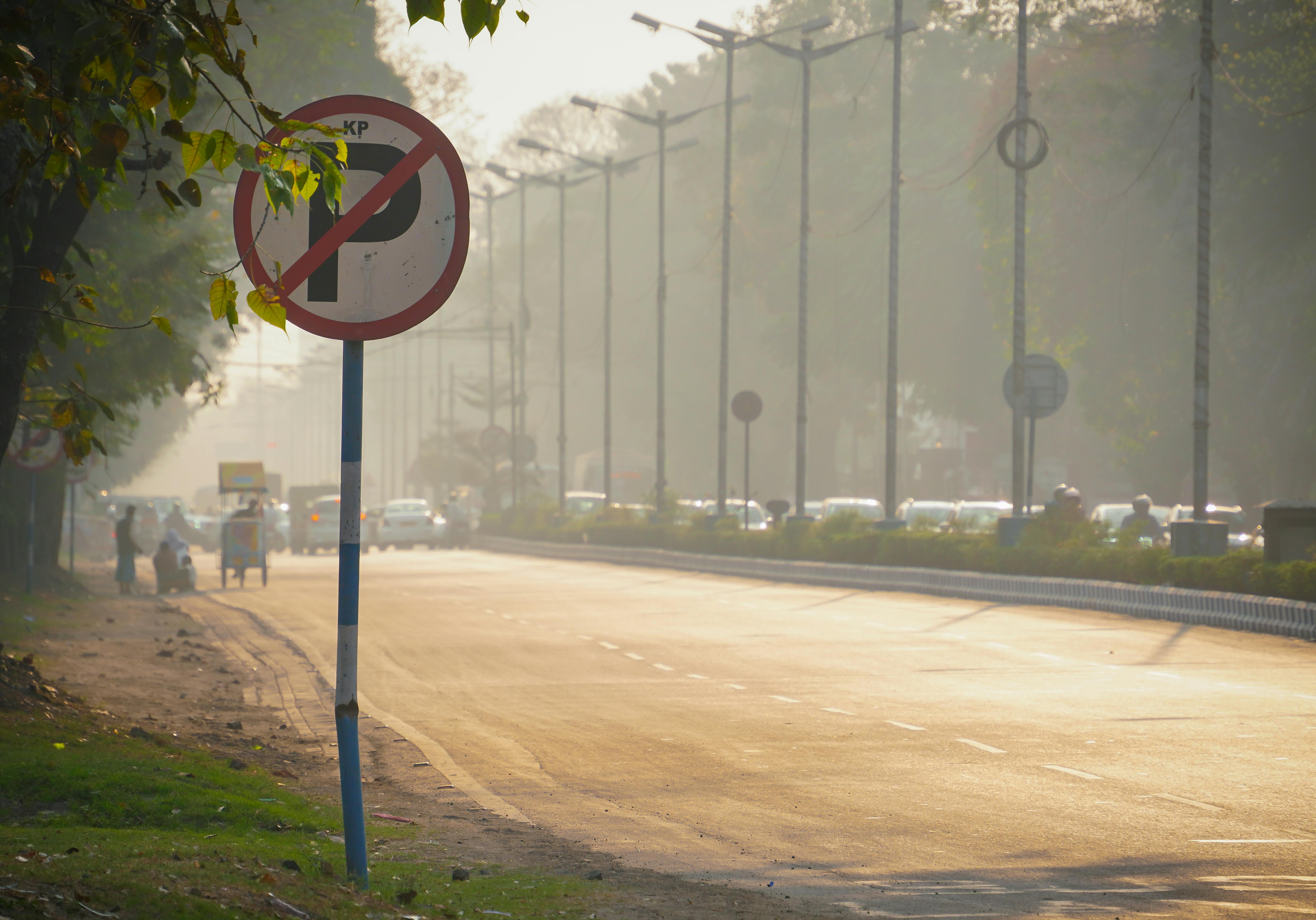 Zadarmo Pohľad na rušnú indickú ulicu so značkou zákazu parkovania, stromami a vozidlami v teplom večernom svetle. Fotka z fotobanky