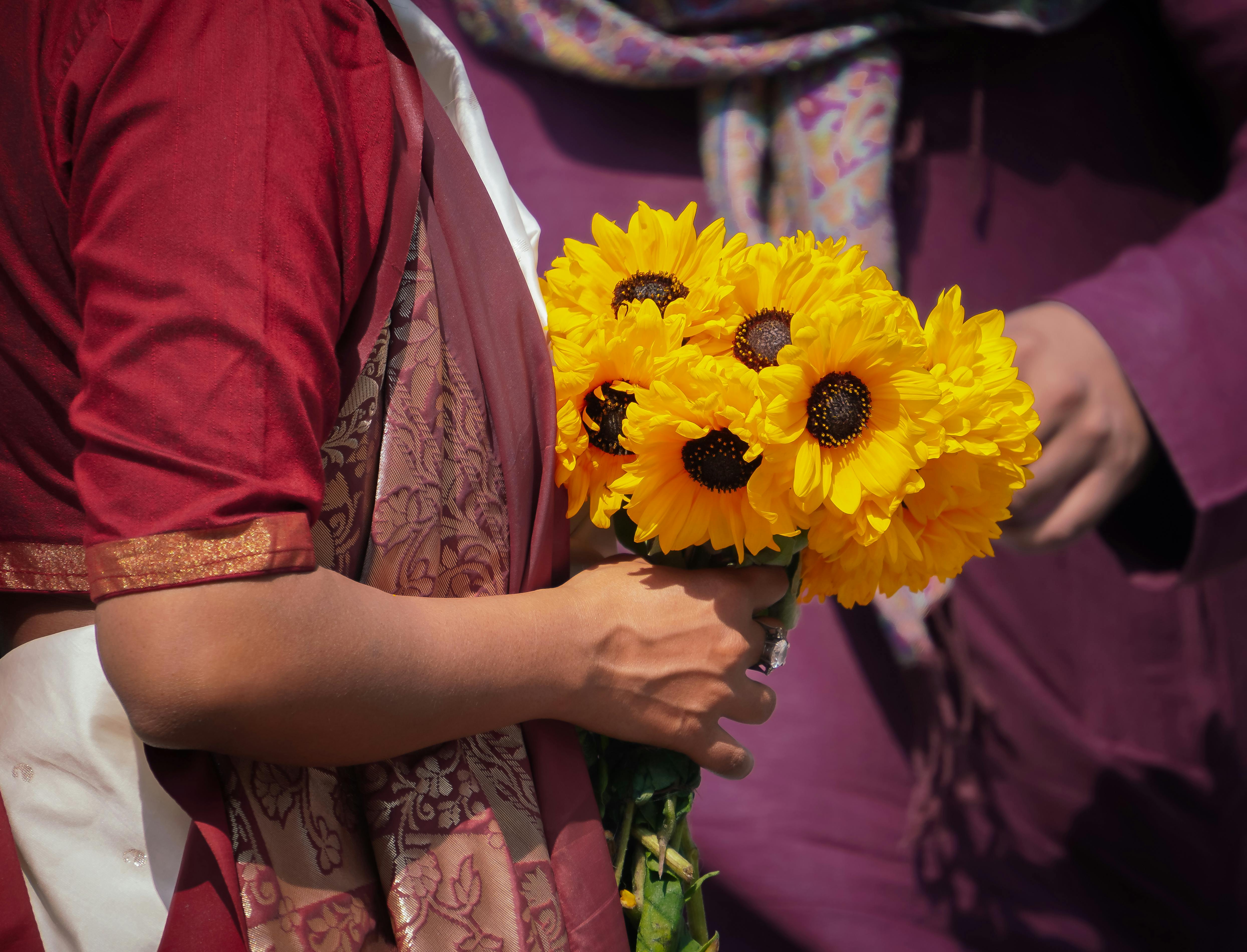 Gratuit Femme en tenue indienne tenant des tournesols aux couleurs éclatantes, illustrant la beauté culturelle. Photos