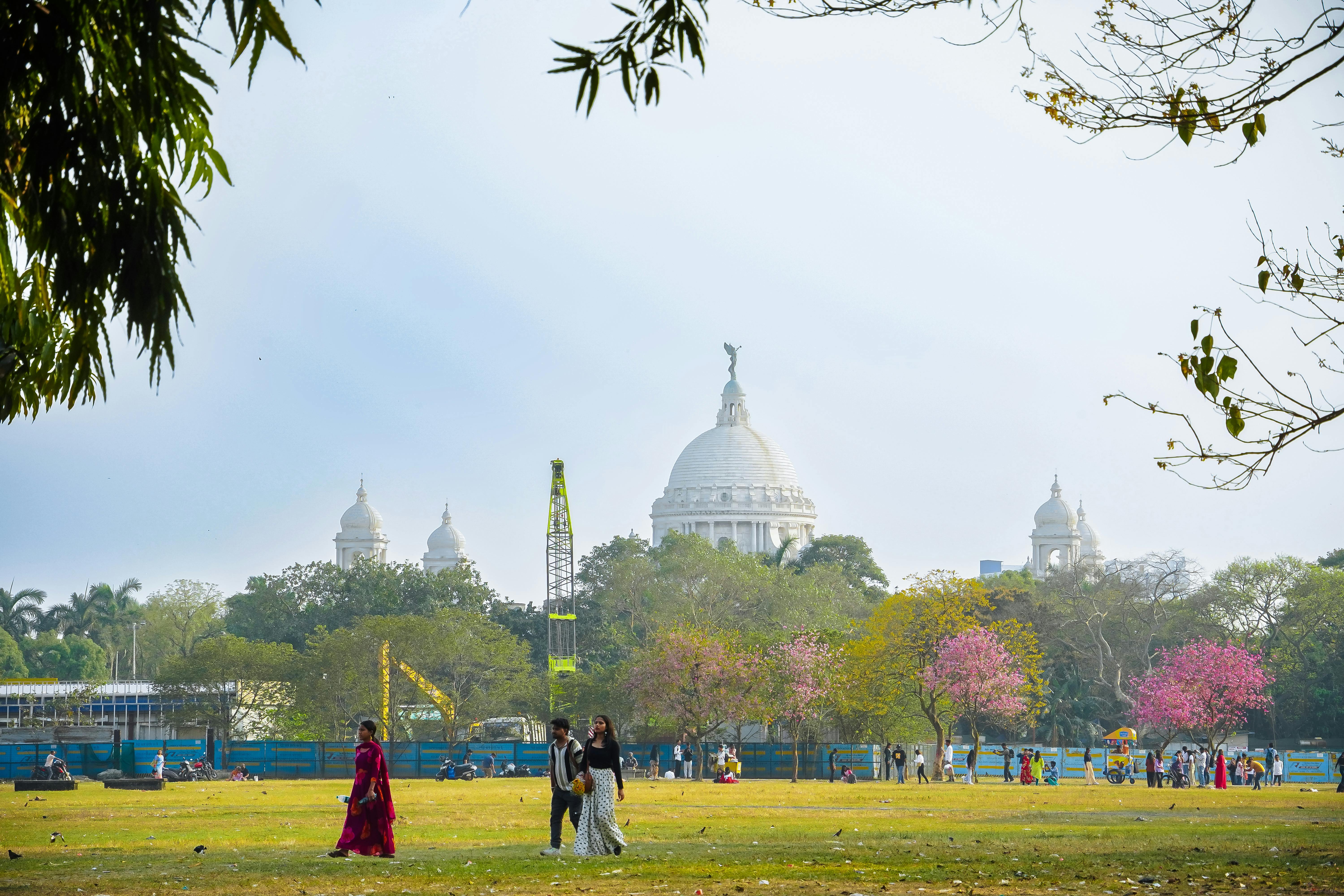 Kostnadsfria Människor njuter av en solig dag vid Victoria Memorial i Kolkata med blommande träd. Stock foto