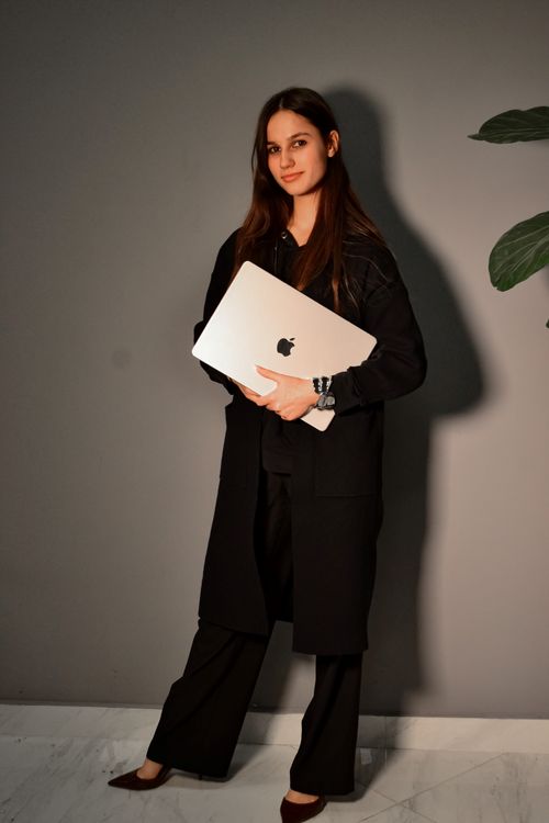 Free Confident woman in black attire holding a laptop indoors. Stock Photo