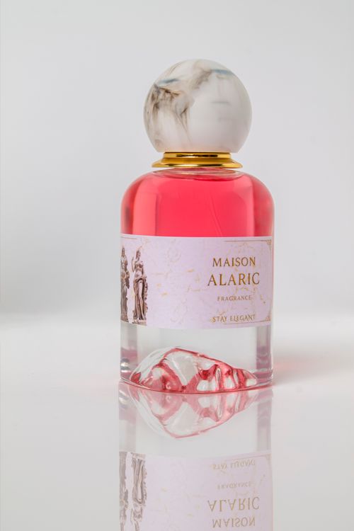 Free Elegant pink Maison Alaric perfume bottle with marble cap on mirrored surface, showcasing luxury and style. Stock Photo