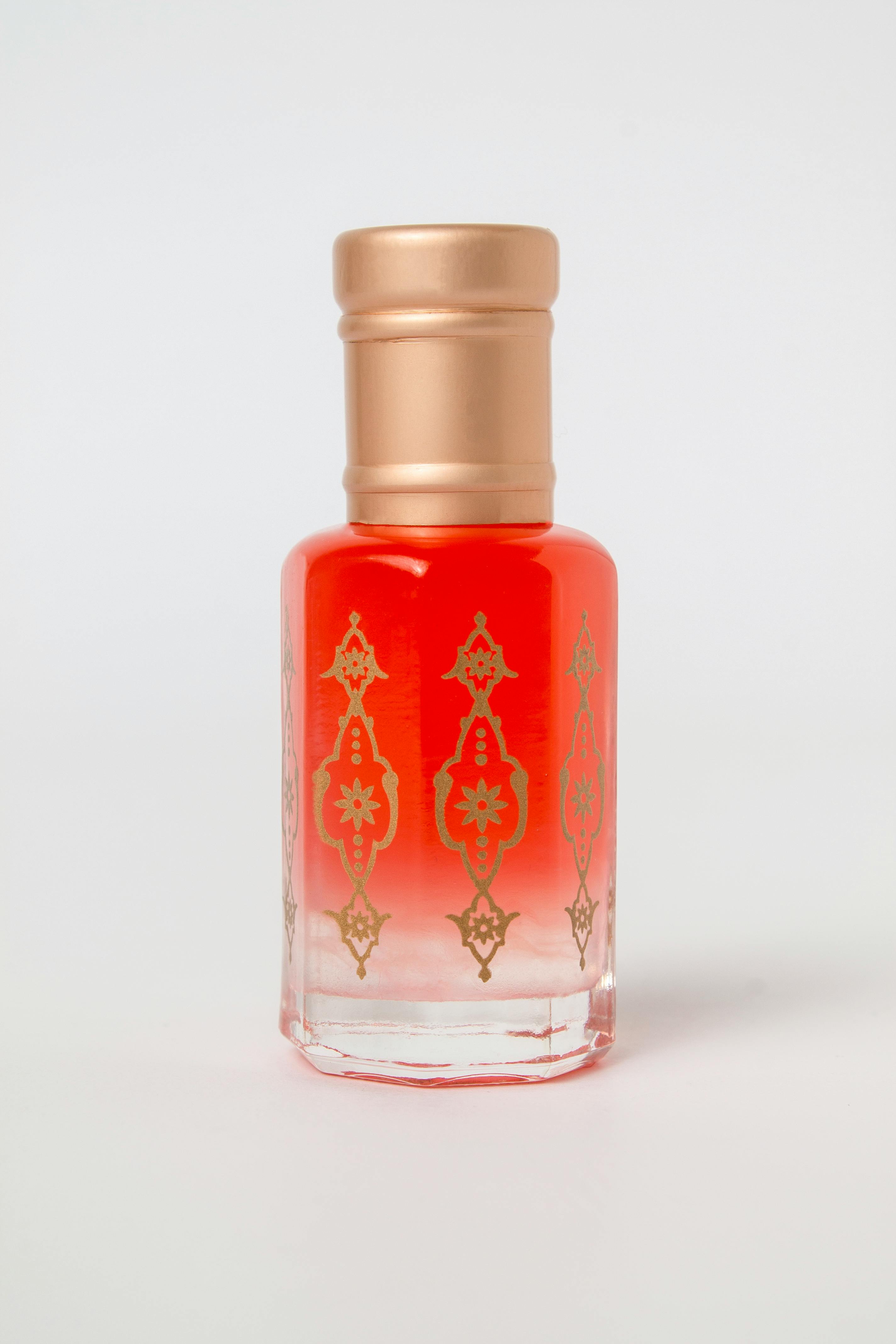 Gratis Fotografía de un elegante frasco de perfume con un elaborado diseño en rojo y dorado. Foto de stock
