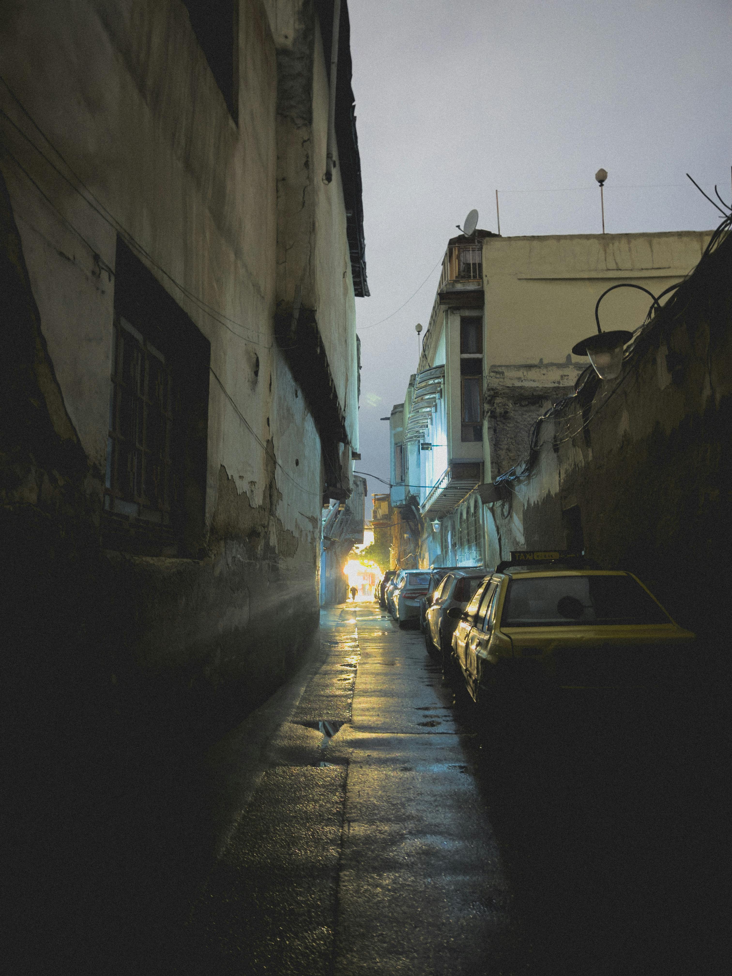 Gratuit Alee îngustă, slab luminată, din Damasc, cu mașini parcate și pavaj ud noaptea. Fotografie de stoc