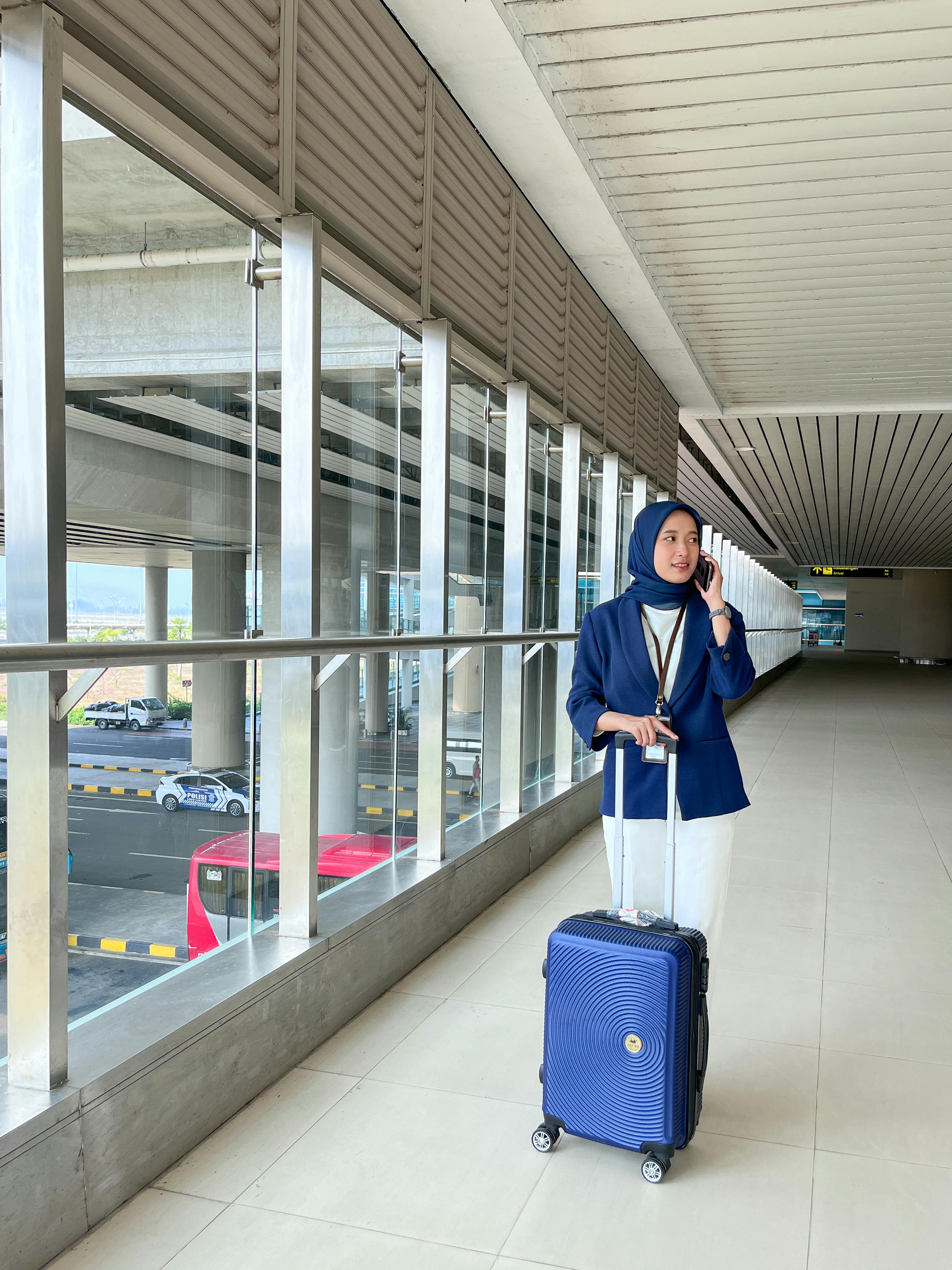 Gratuit Femme d'affaires sûre d'elle, vêtue de bleu, parle au téléphone à l'aéroport indonésien. Concept de style de vie alliant voyage et affaires. Photos