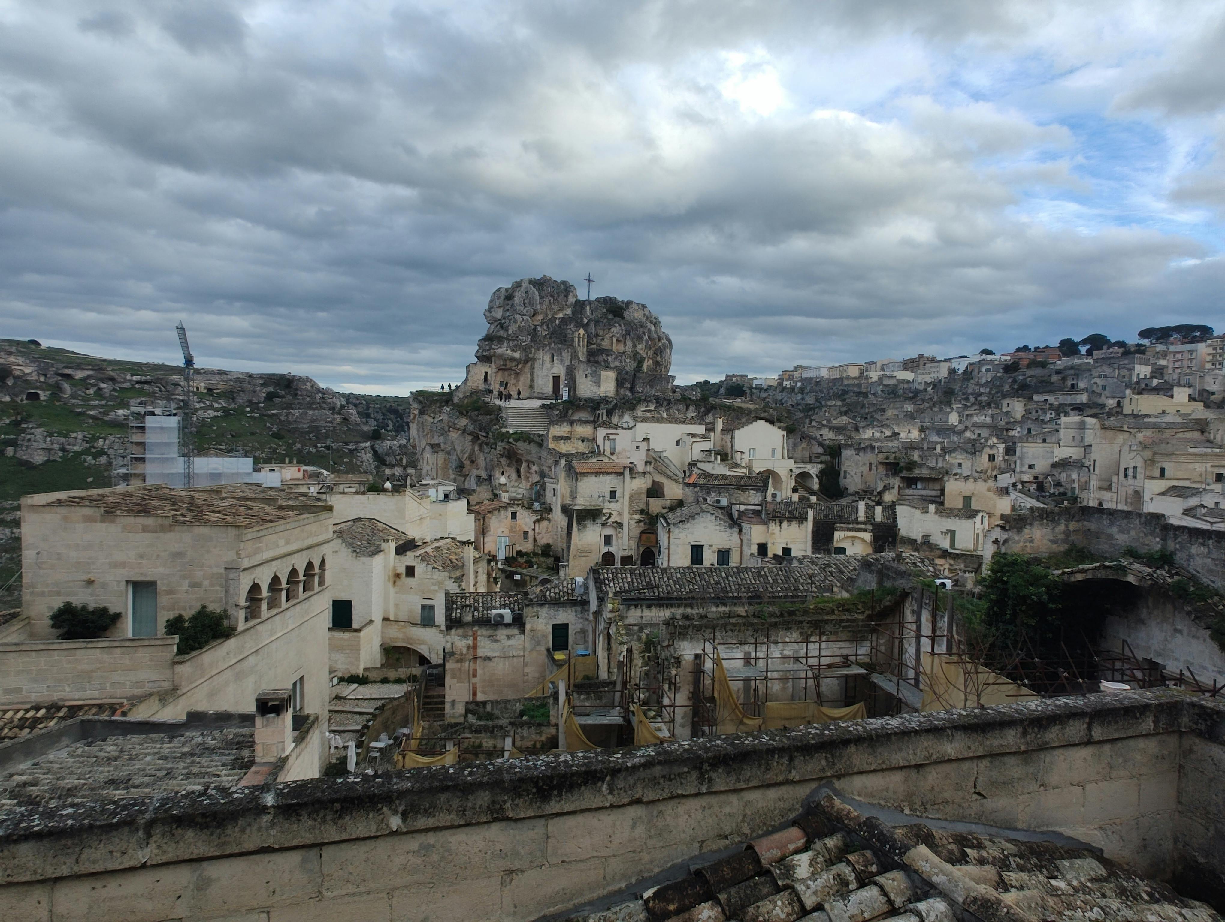 無料 曇り空の下、古代マテーラのサッシ地区を眺める。象徴的な石造建築が際立っている。 写真素材