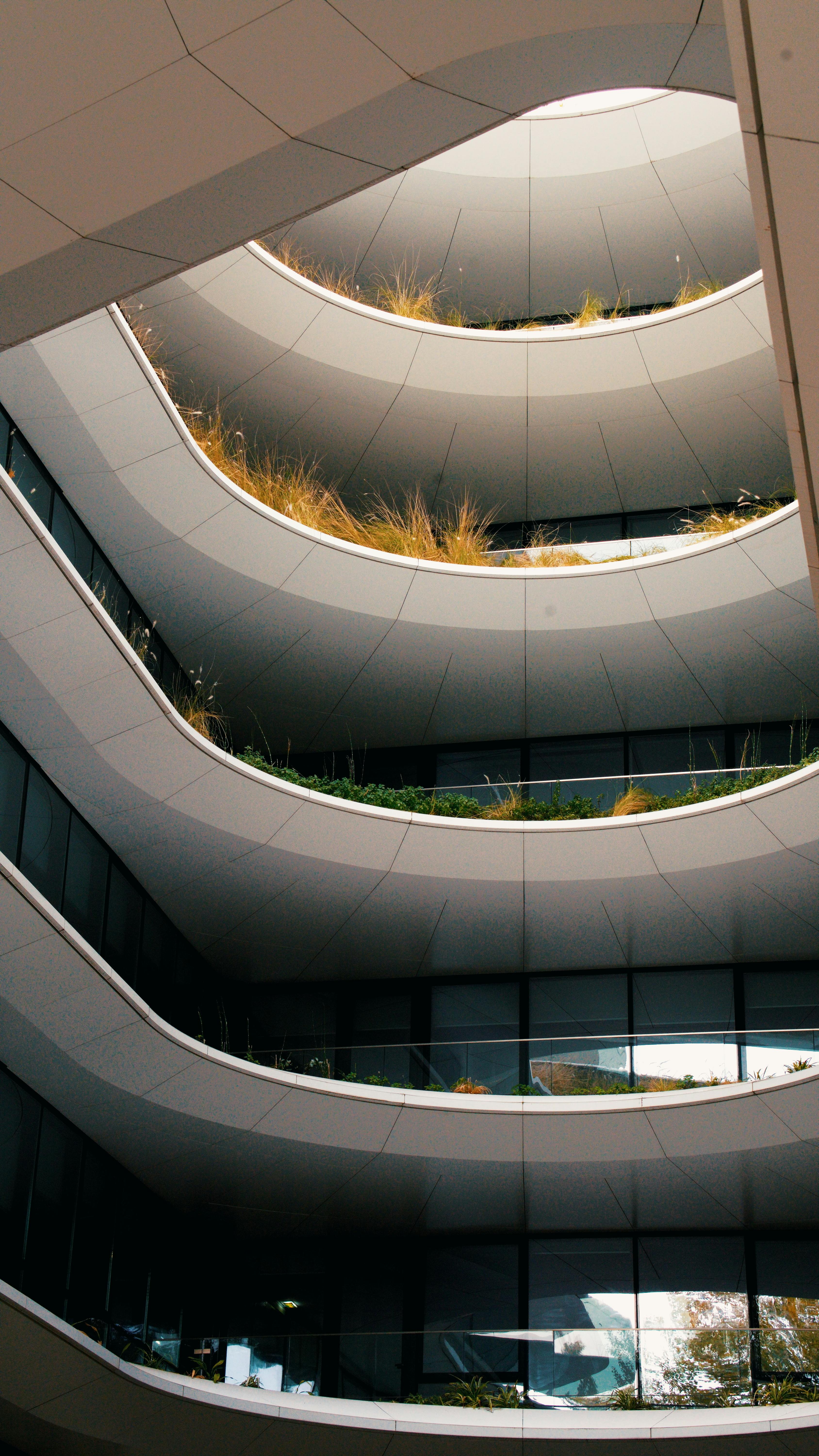 De franc Vista impressionant d'un edifici contemporani de diverses plantes amb balcons corbats únics amb vegetació natural. Foto d'estoc