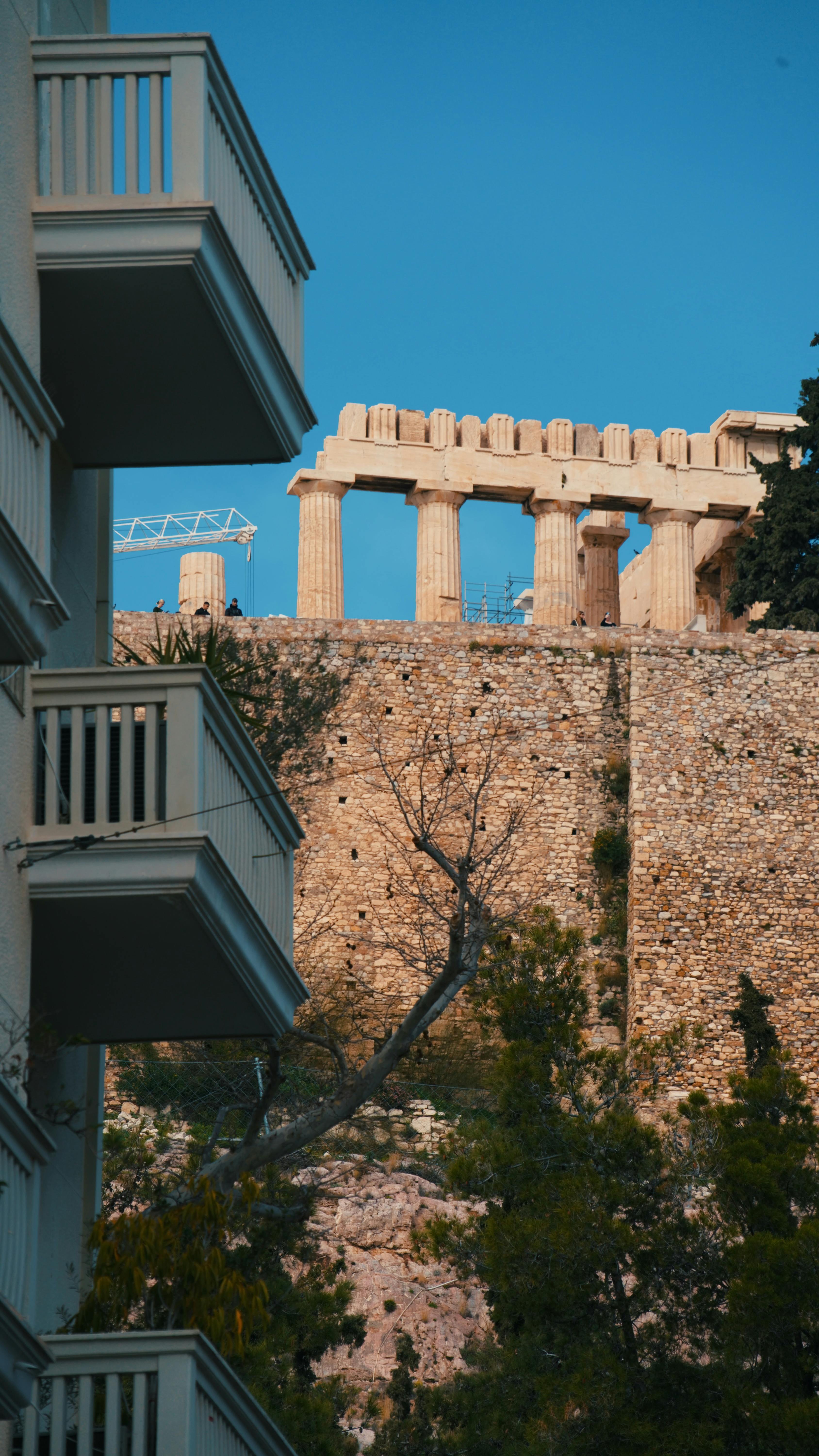 Kostnadsfria Parthenon står sida vid sida med en modern byggnadsbalkong, som symboliserar antika och moderna kontraster. Stock foto